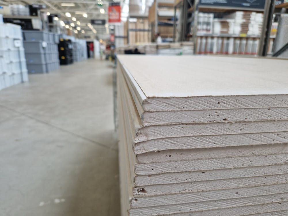 A stack of drywall sheets sits in a warehouse.