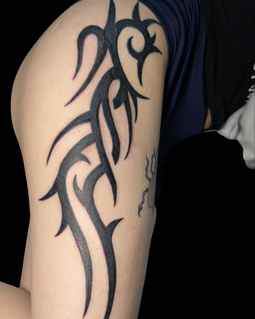 Tattoo of a skull with a snake wrapped around it, with smoke-like details around the design.