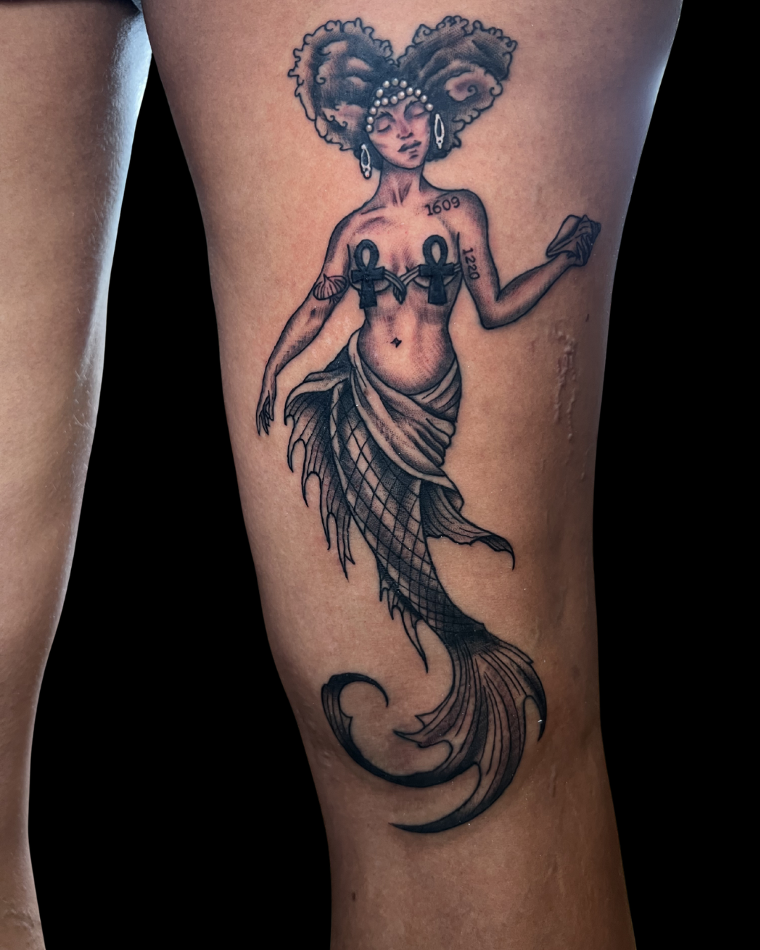 Tattoo of a fierce, colorful jaguar head with its mouth open, showing teeth and tongue, on a person's thigh.