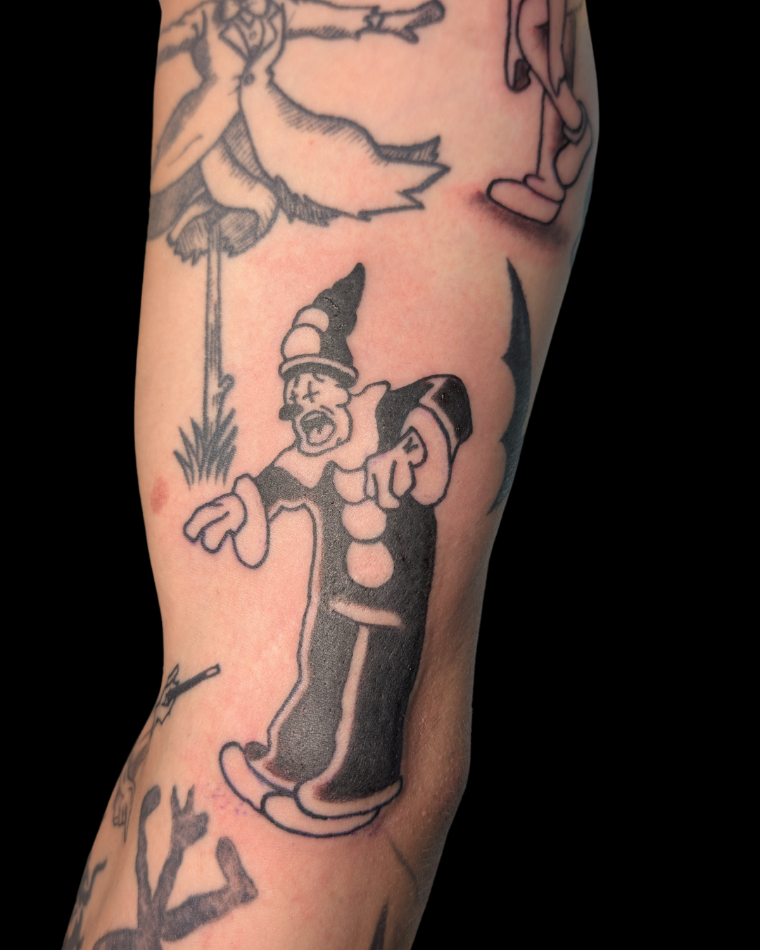 Colorful tattoo of two cats surrounded by flowers and foliage on a person's forearm.