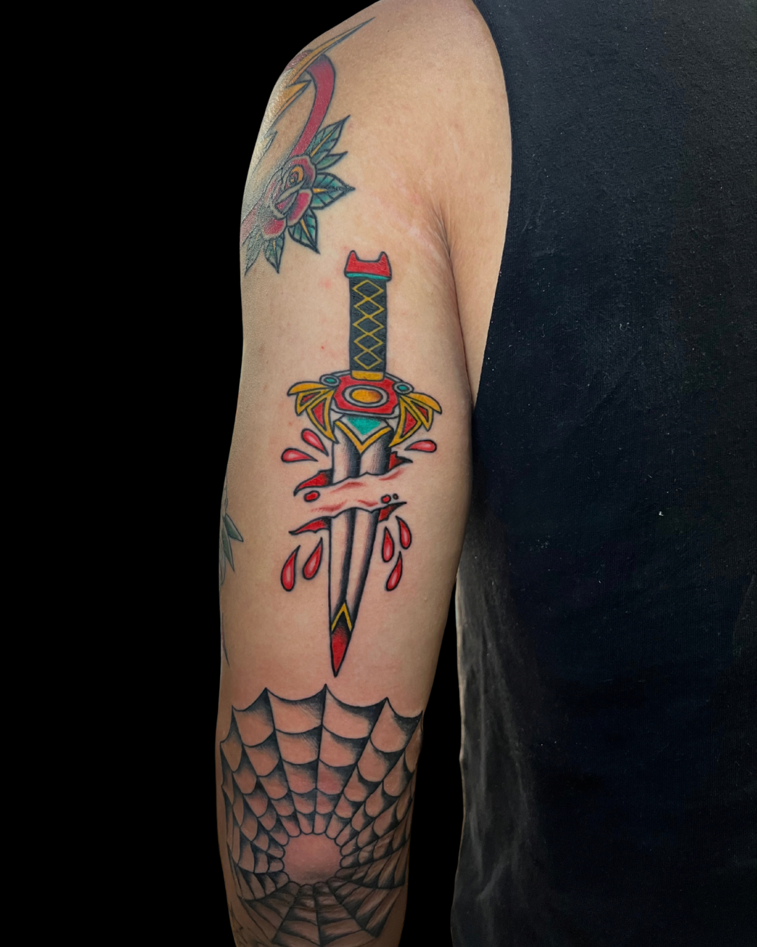 Colorful tattoo of two cats surrounded by flowers and foliage on a person's forearm.