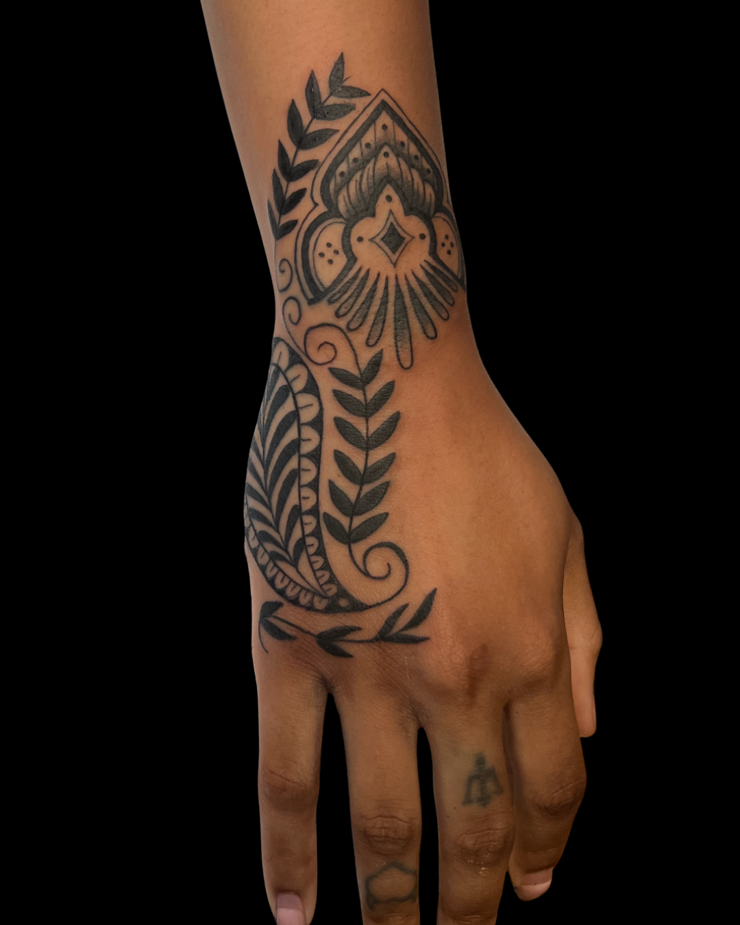 Tattoo of a guitar, sunflower, purple rose, and white rose on a person's arm with a brick wall in the background.