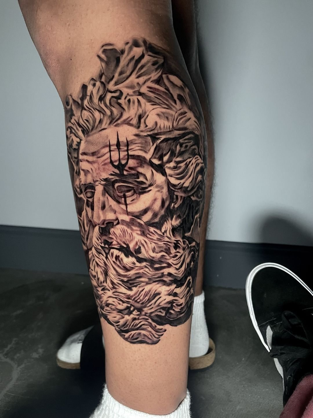 Tattoo of a skull with a snake wrapped around it, with smoke-like details around the design.
