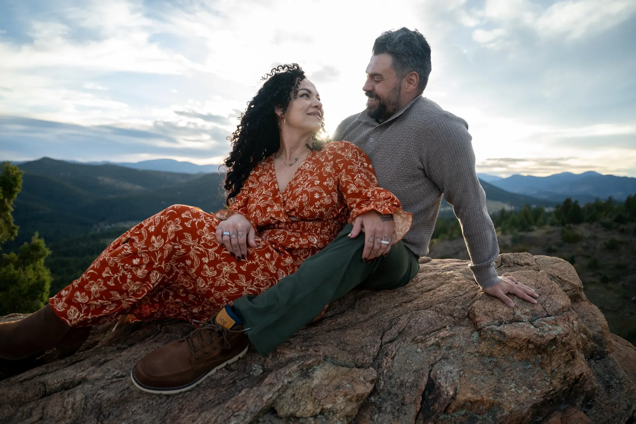 Couple sharing an intimate moment on a rocky overlook with sweeping Colorado mountain views during a sunset family photography session at Mount Falcon West near Denver.
