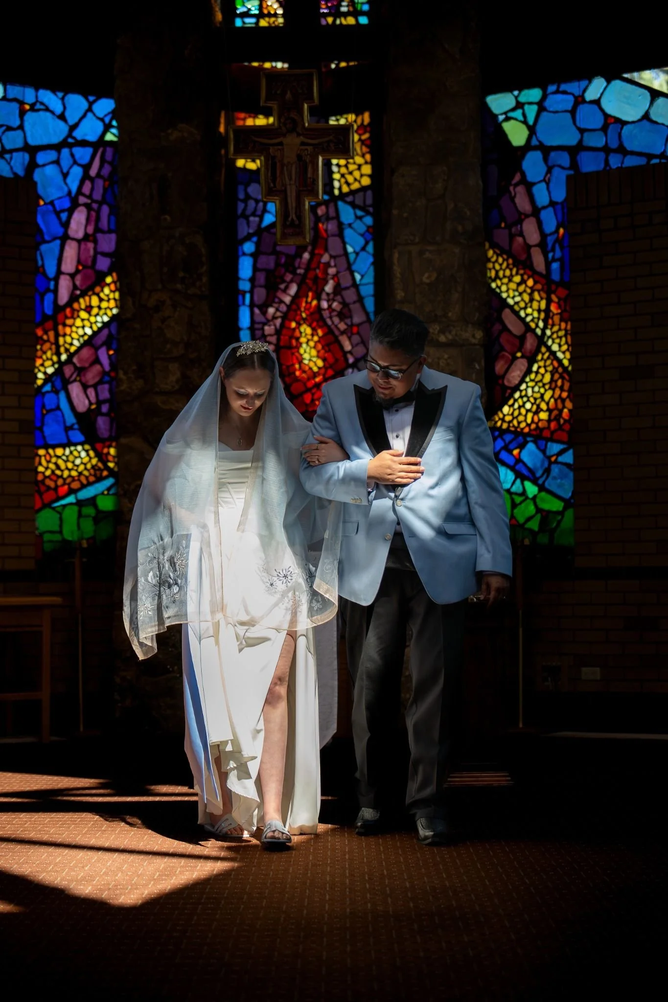 Walking the Aisle. Beautifully moody and artistic elopement photography in a Catholic church setting—quiet, sacred moments captured with dramatic composition by Ryan Kost.