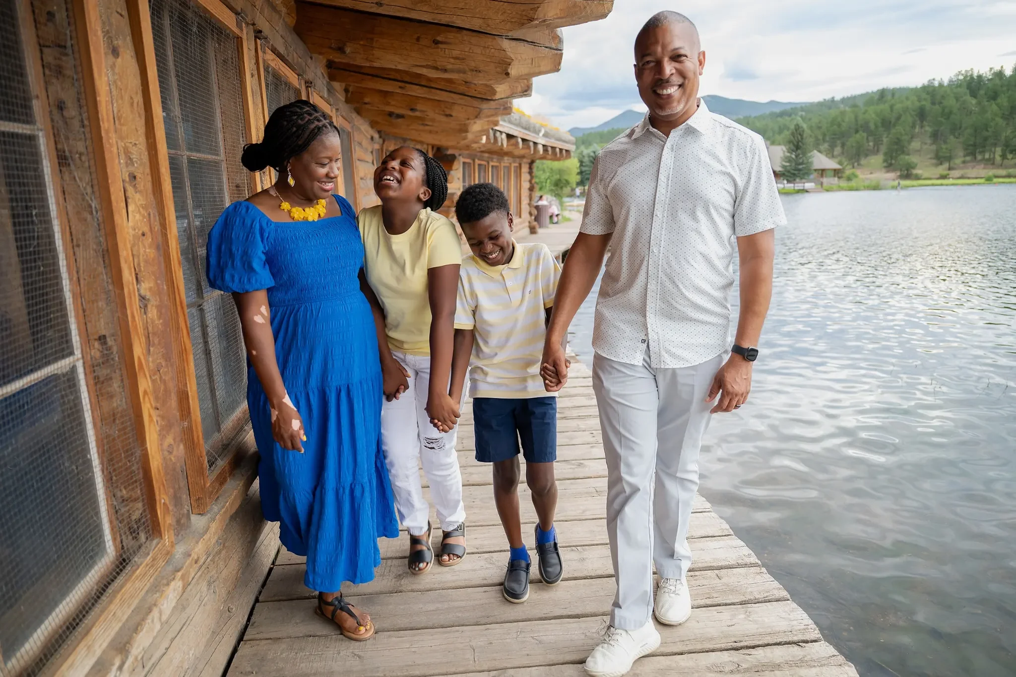 A family shares natural laughter walking boardwalk at Evergreen Lake in Colorado. Summer relaxed, natural family portrait photography captured by Ryan Kost