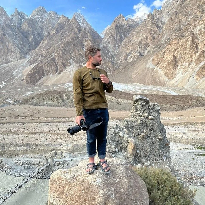 Ryan Kost, Colorado photographer standing with his camera in front of the Passu Cones in Northern Pakistan.