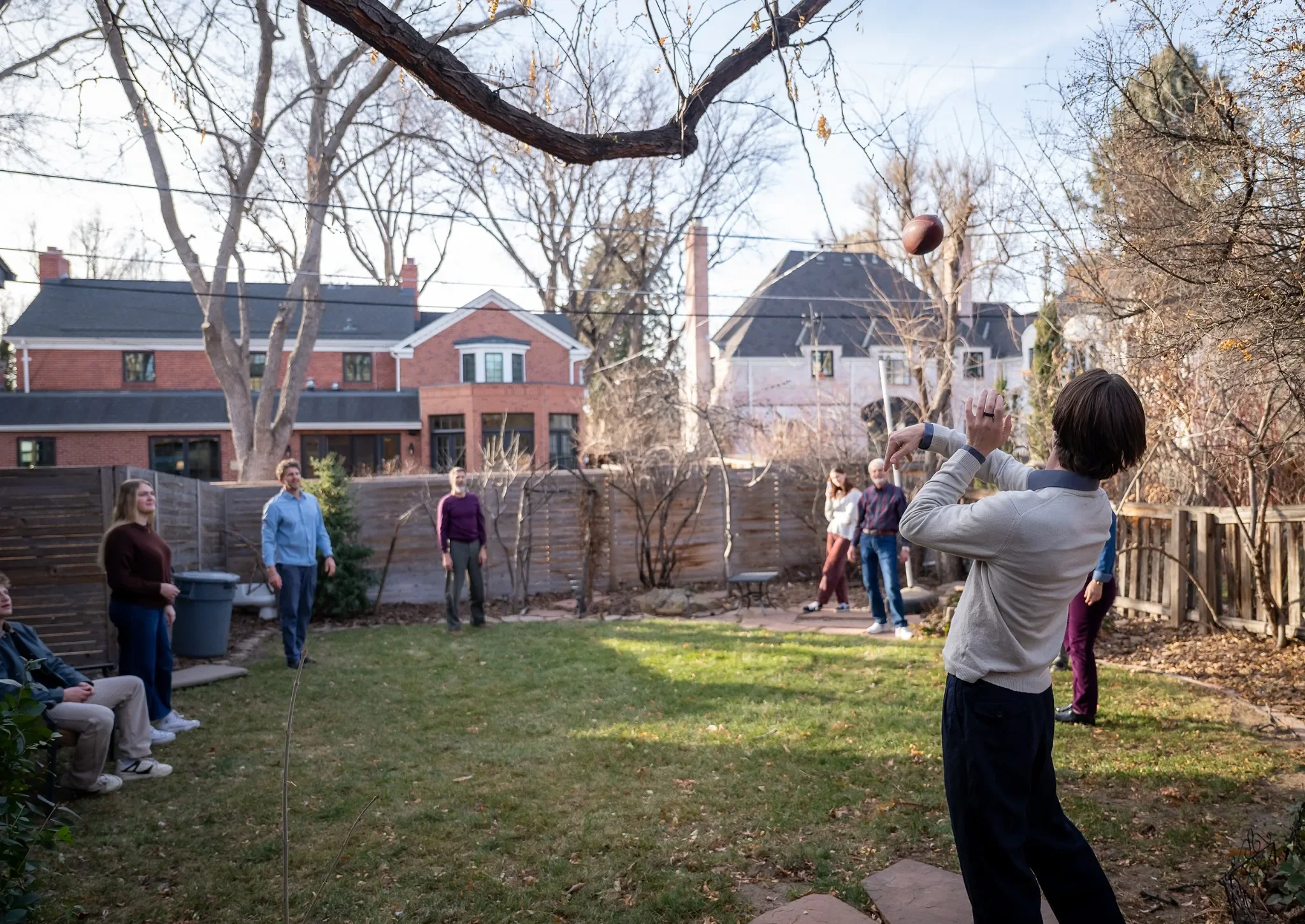 Family throwing football in backyard in Denver, Colorado. Documentary family photography by Ryan Kost.