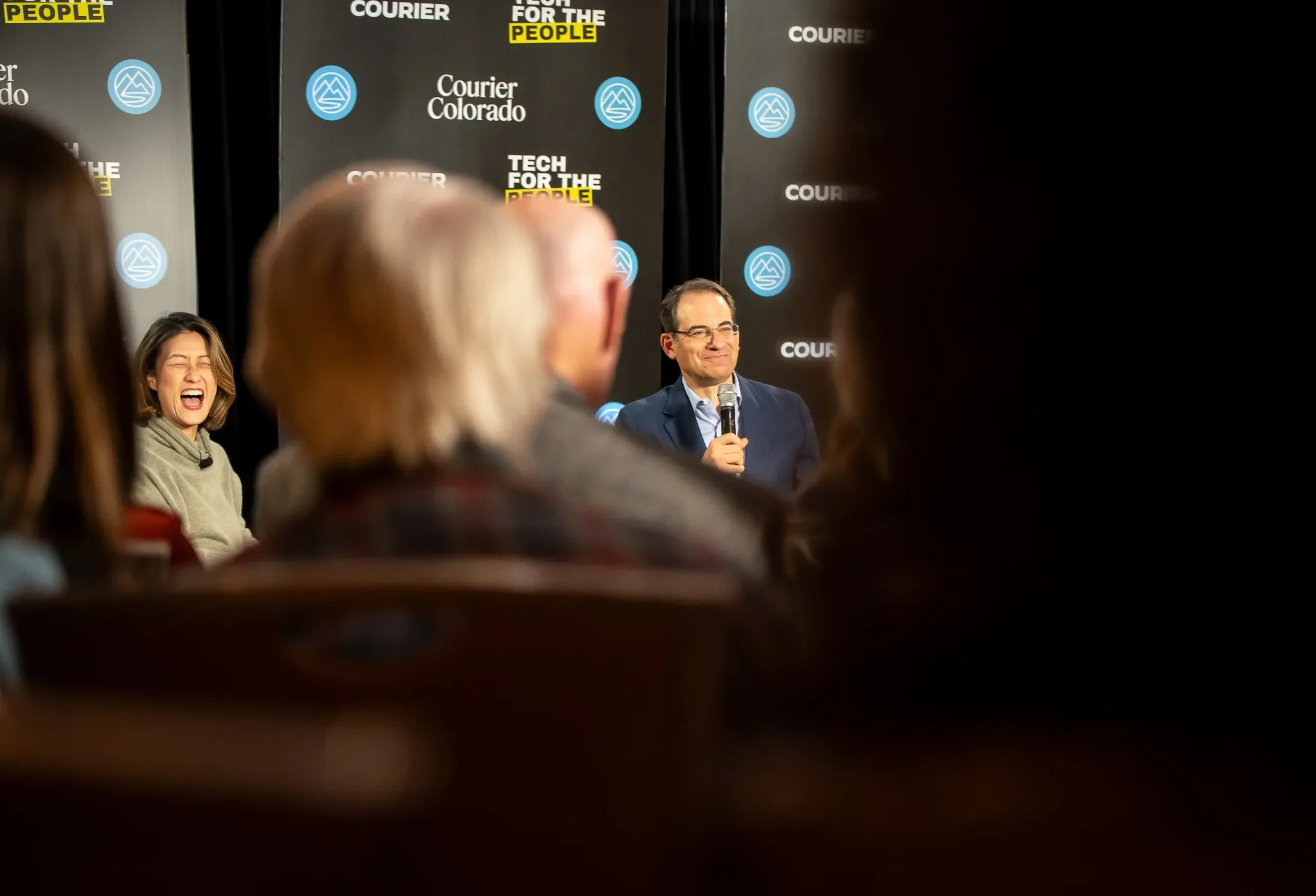 Katie Phang laughs as Colorado Attorney General Phil Weiser speaks during the Courier Colorado Get Out the Ballot event in Westminster, Colorado, photographed by Ryan Kost.