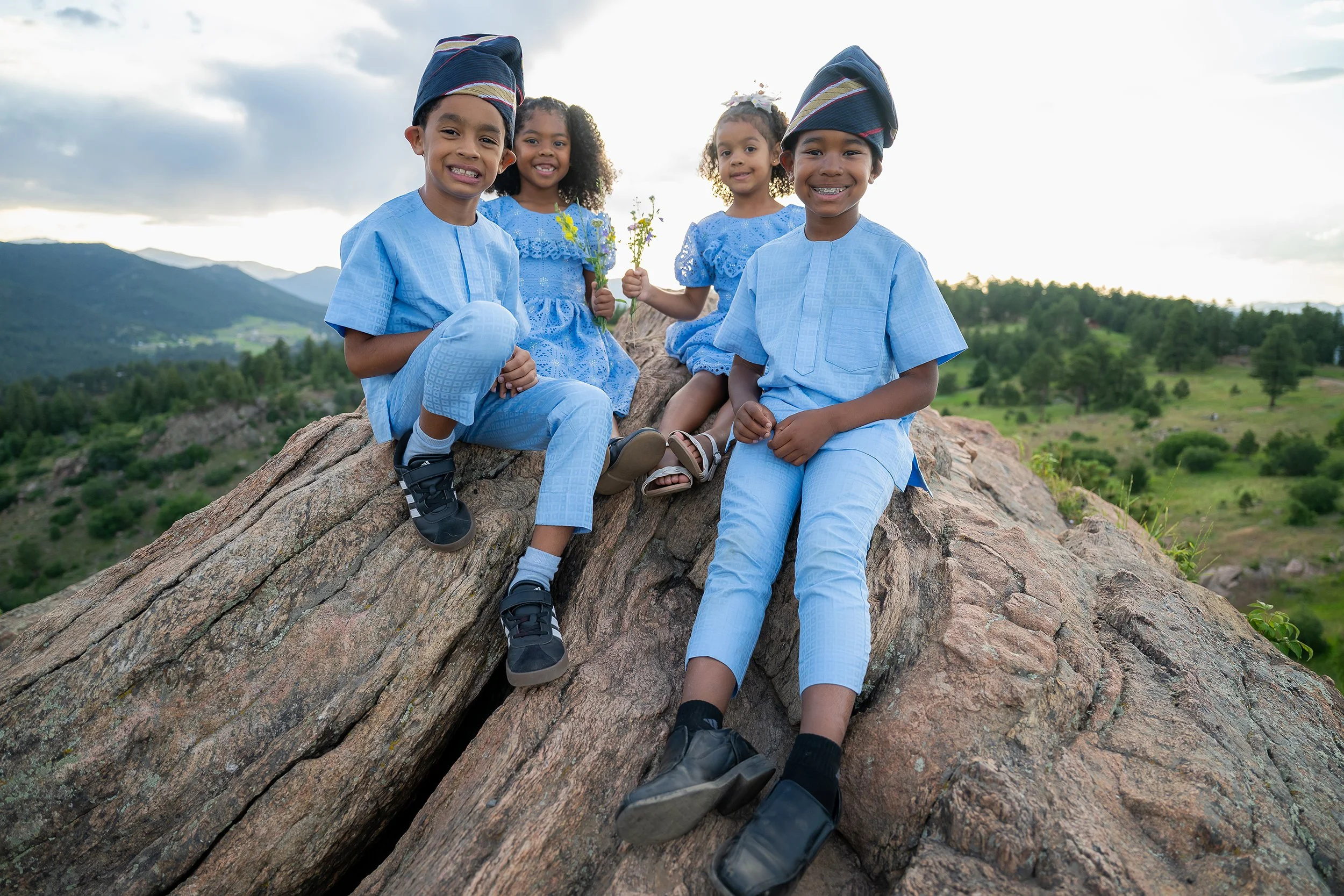 Siblings and cousins sitting on rocks together in beautiful summer light at Mount Falcon West Trailhead in Colorado. Captured by Ryan Kost