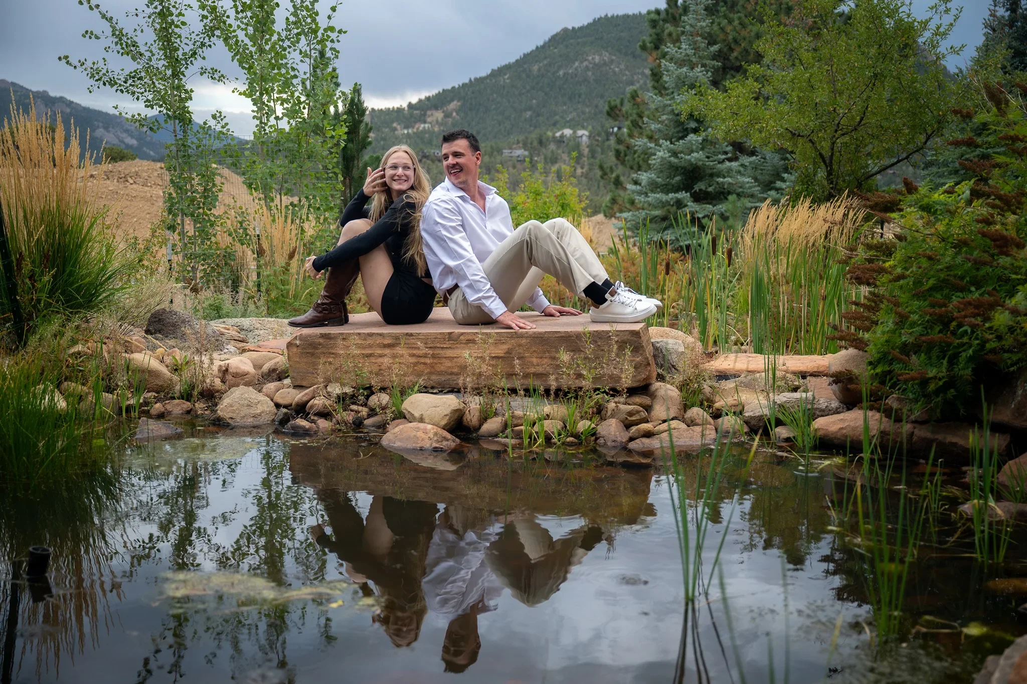 Couple sitting on rocks during a surprise engagement proposal session at the Stanley Hotel in Estes Park, Colorado captured by Ryan Kost