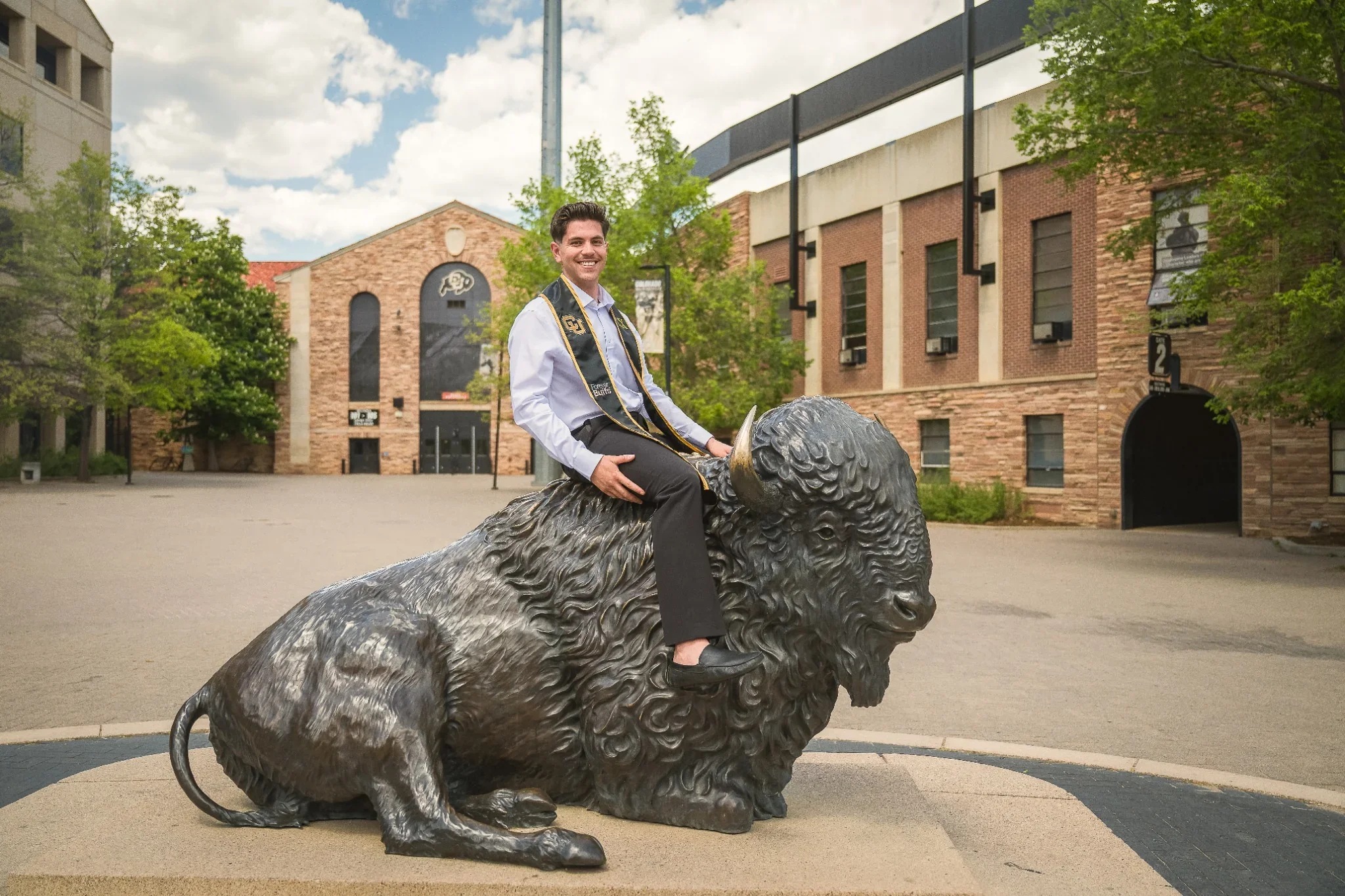 University of Colorado senior graduation portrait riding Ralphie the bison statue outside of the football stadium on campus. Ryan Kost Photography
