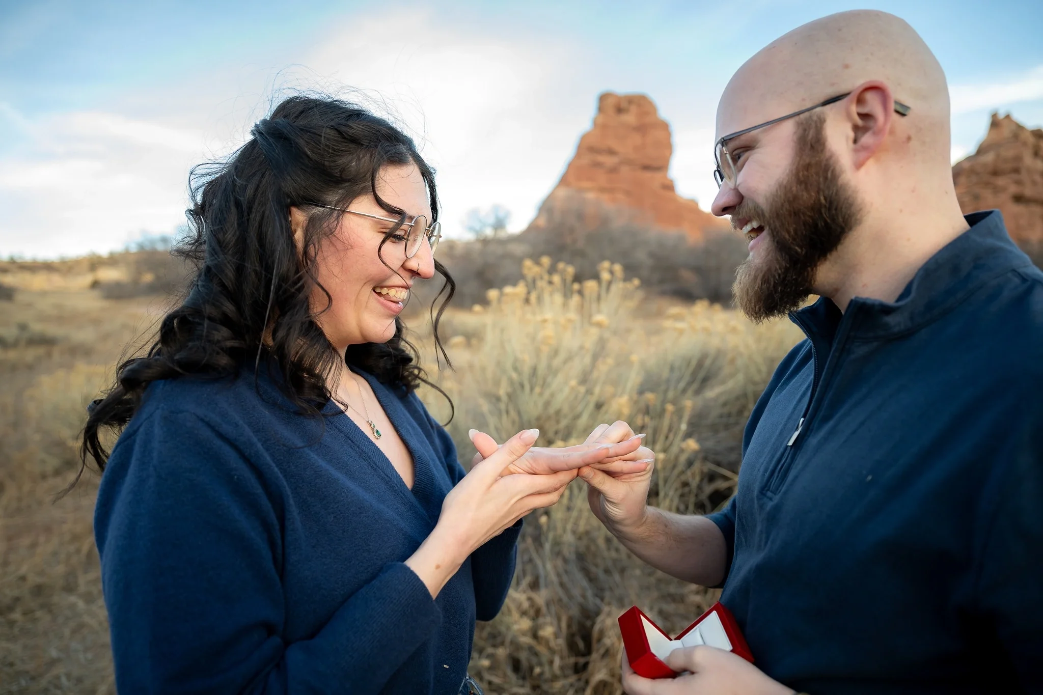 Emotional engagement photo of a couple exchanging rings outdoors at South Valley Park in Littleton, Colorado photographed by Ryan Kost