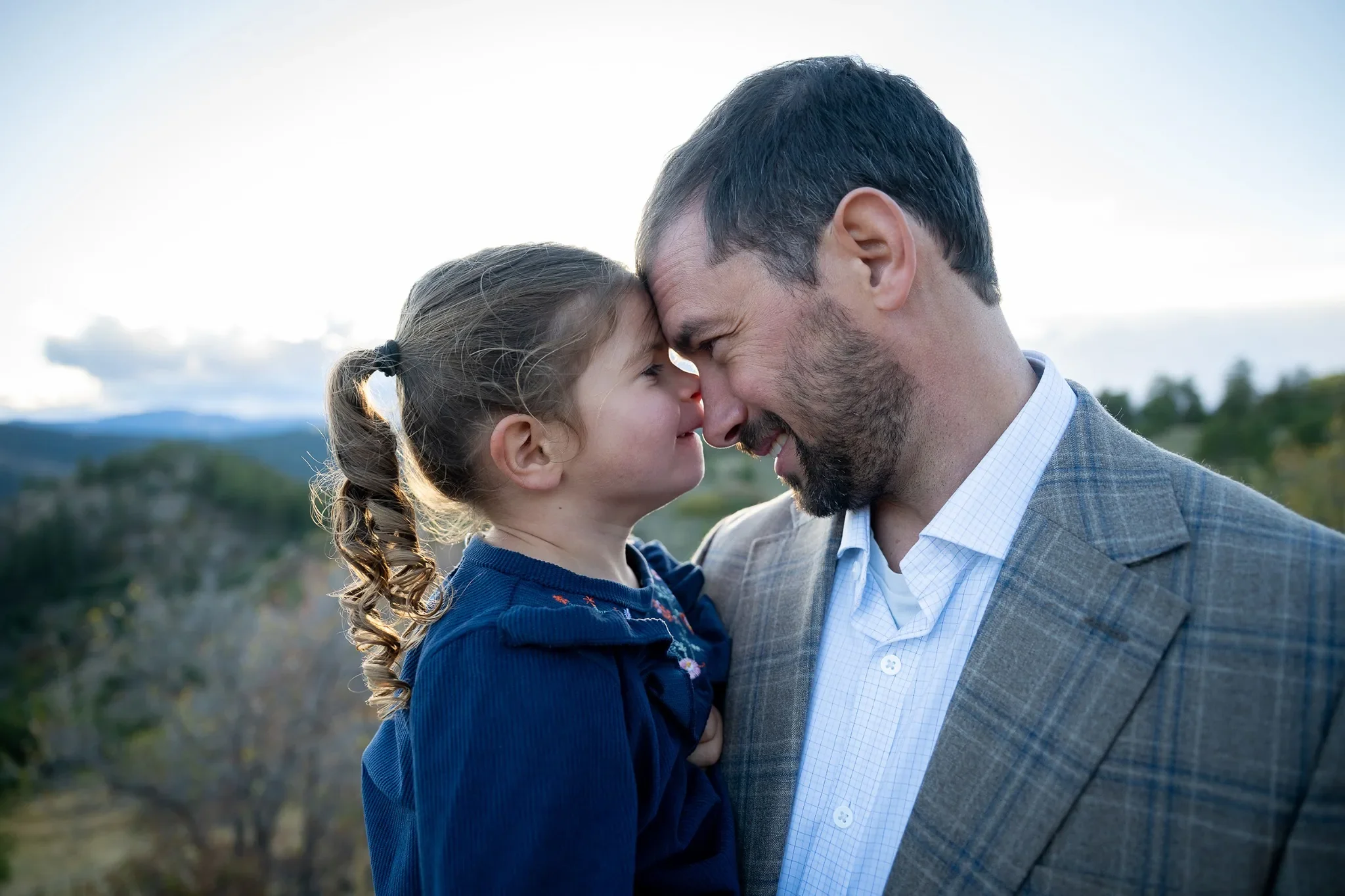 Dad and daughter nose to nose outdoor portrait during a relaxed family photo session at Mount Falcon West in the Denver foothills. Ryan Kost Photography