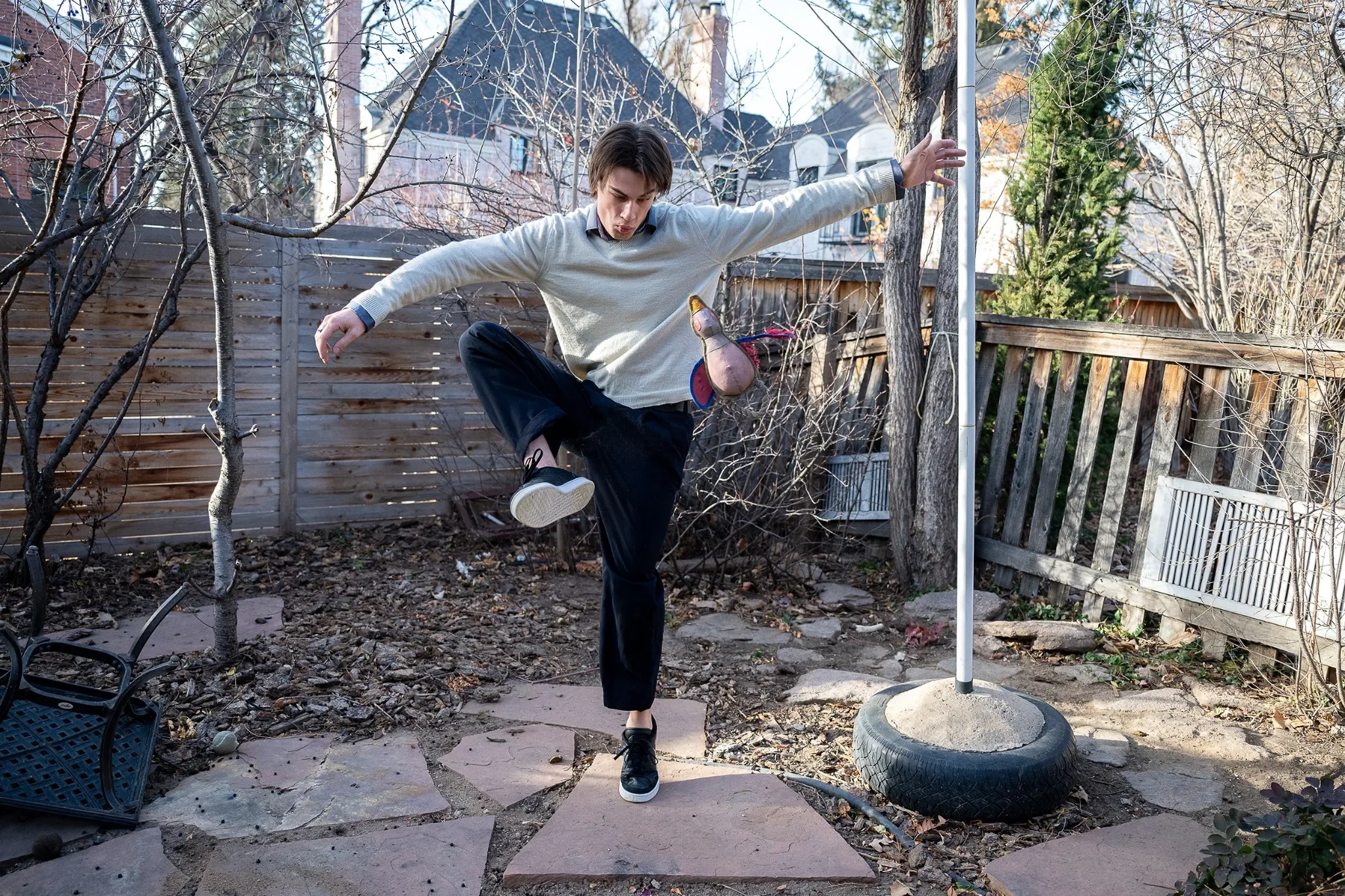 Fun action portrait in backyard juggling dog's toys during an in home holiday family photo session in Denver, Colorado captured by Ryan Kost