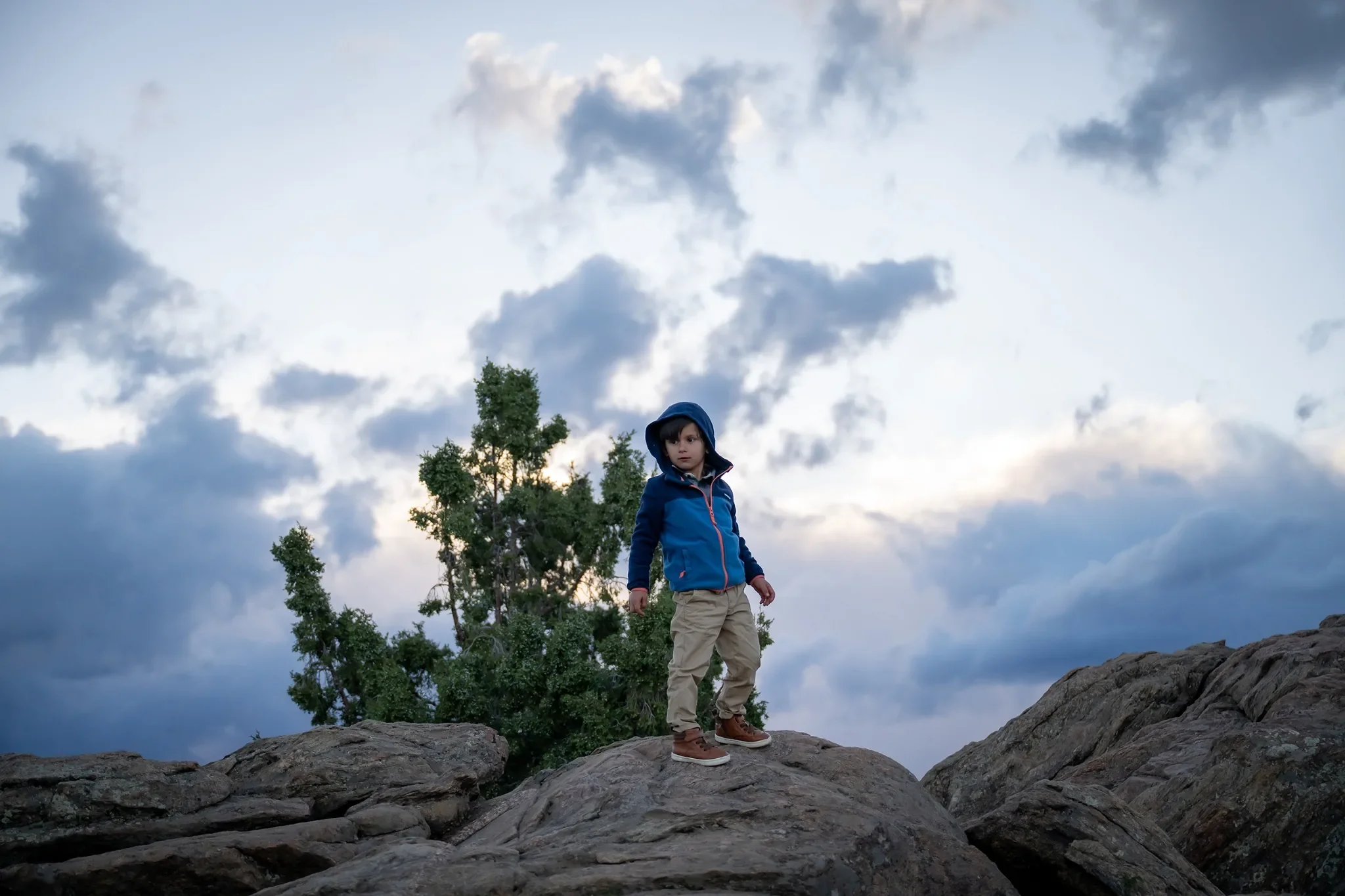 The little explorer posing on a rock outcropping during a adventurous outdoor family photo session at Mount Falcon West in the Denver foothills. Ryan Kost Photography.