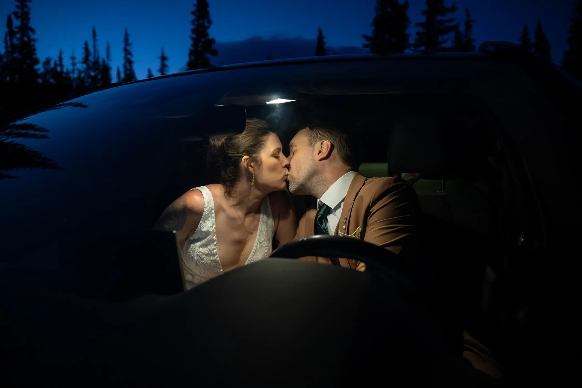 Newlyweds sharing an intimate kiss in car at Brainard Lake Trailhead at night after elopement. Ryan Kost Photography