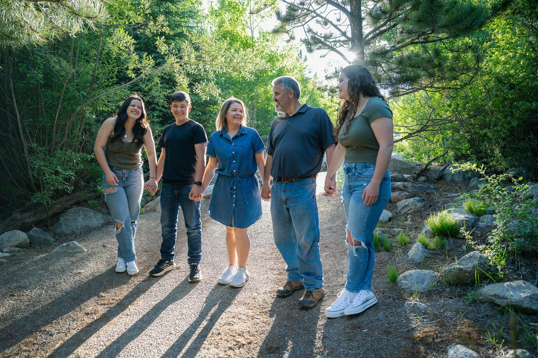 Family holding hands under dramatic Colorado Summer golden light at Alluvial Fan in Rocky Mountain National Park.  Natural, relaxed family photography captured by Ryan Kost
