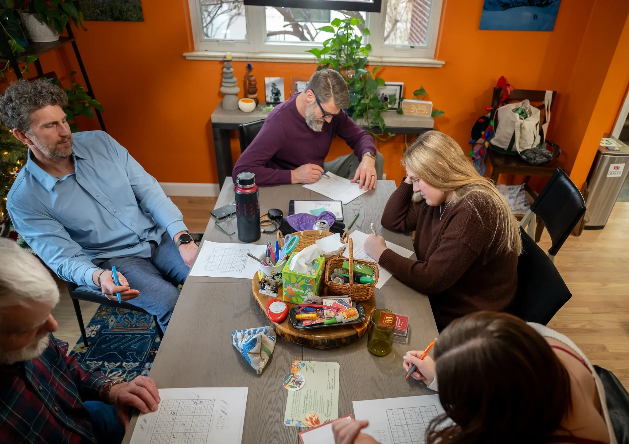 Denver documentary family photography captured by Ryan Kost.  A family plays sudoku during a in home holiday photo session.