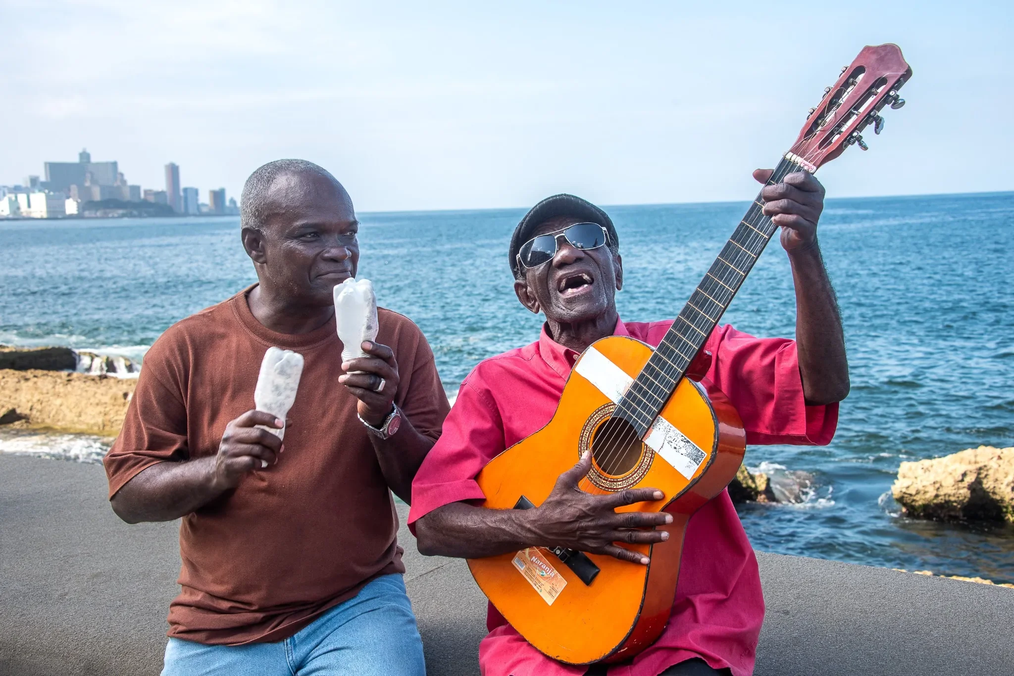 Music is the spirit of Cuba.  Portrait on Malecon in Havana strumming guitar and singing songs. Ryan Kost Photography.