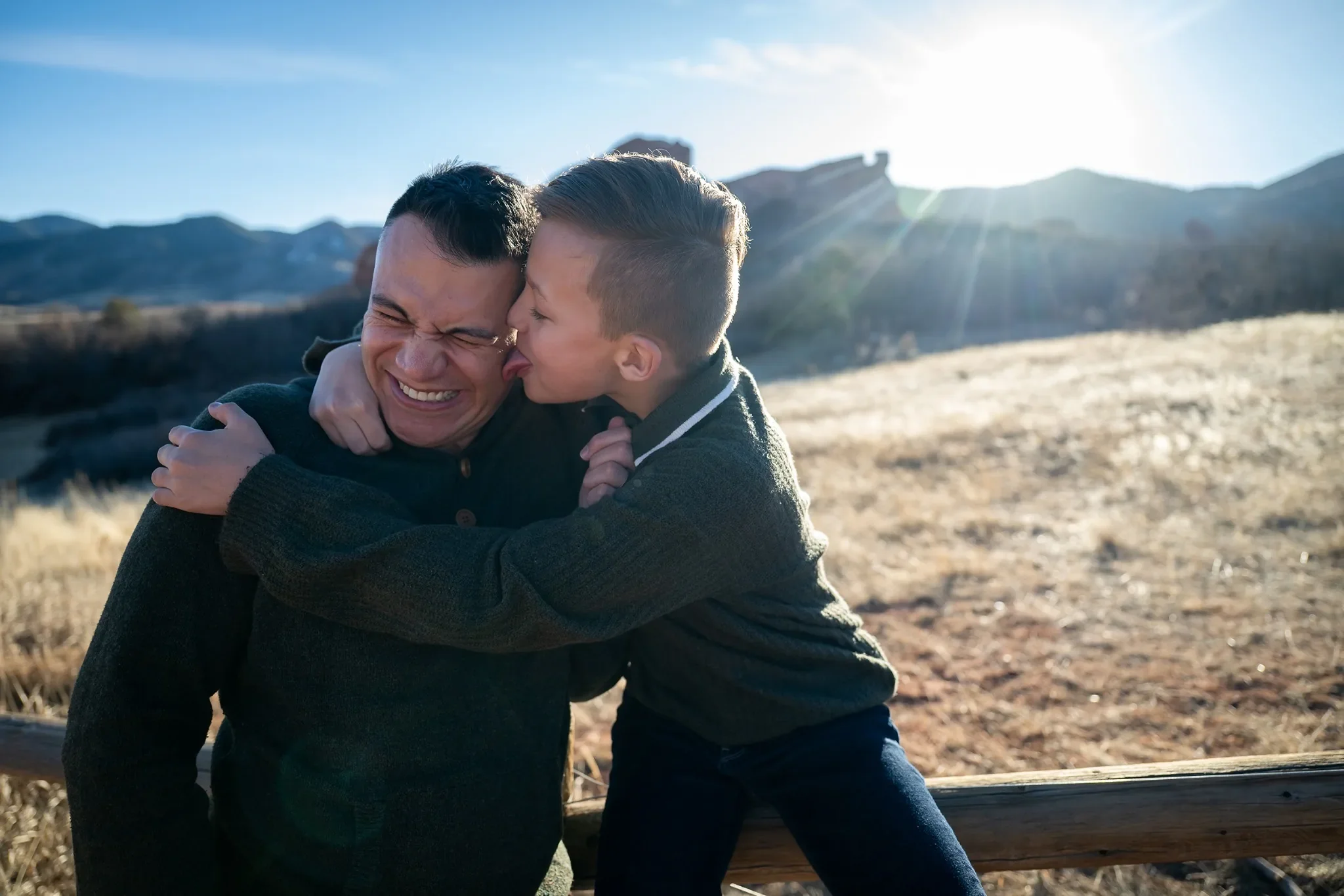 Silly portrait licking dad's cheeks. Outdoor family photography session at South Valley Park Littleton Colorado.