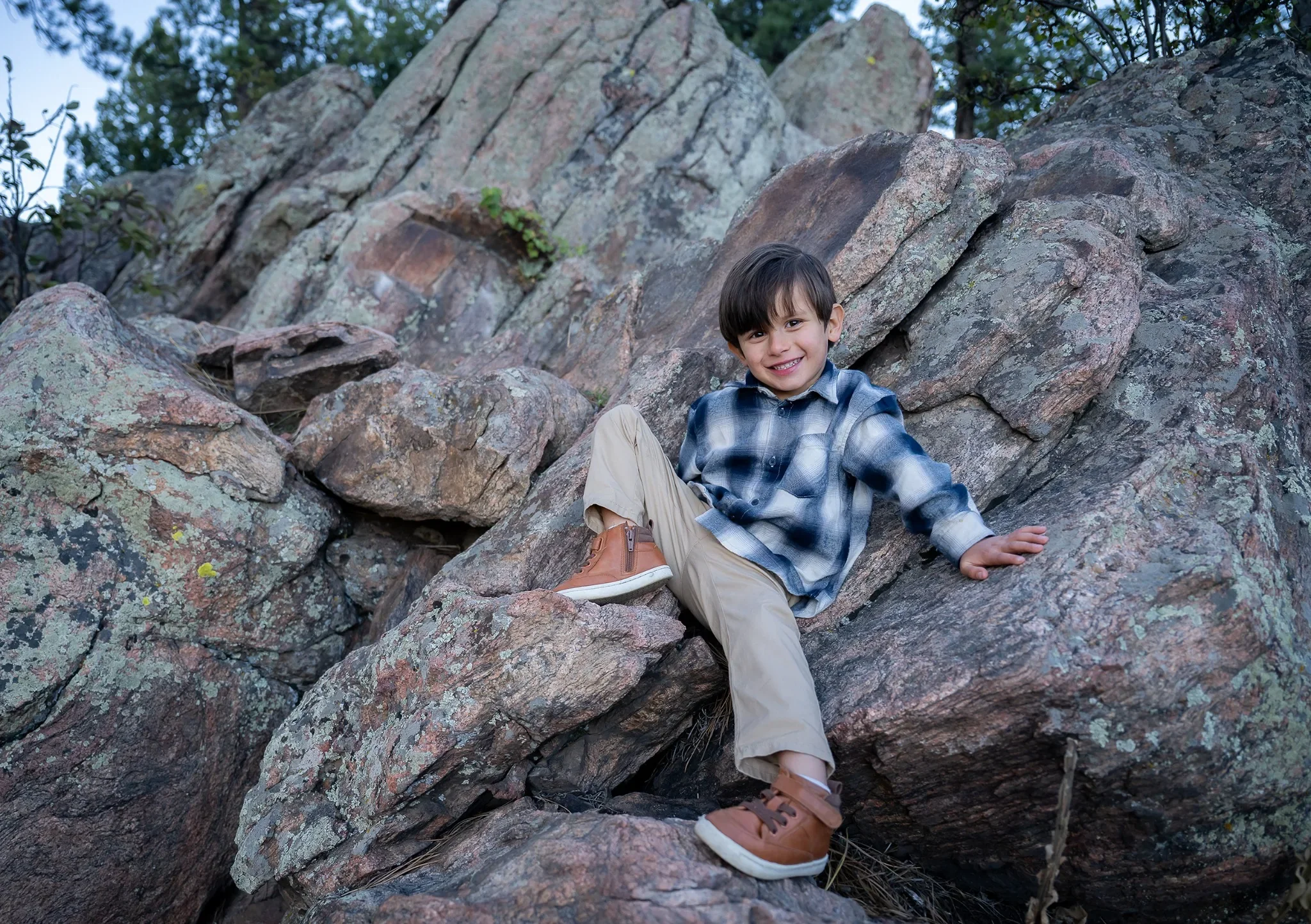 A cute, natural family portrait of boy climbing rocks at Mount Falcon West in the Denver foothills captured by Ryan Kost.
