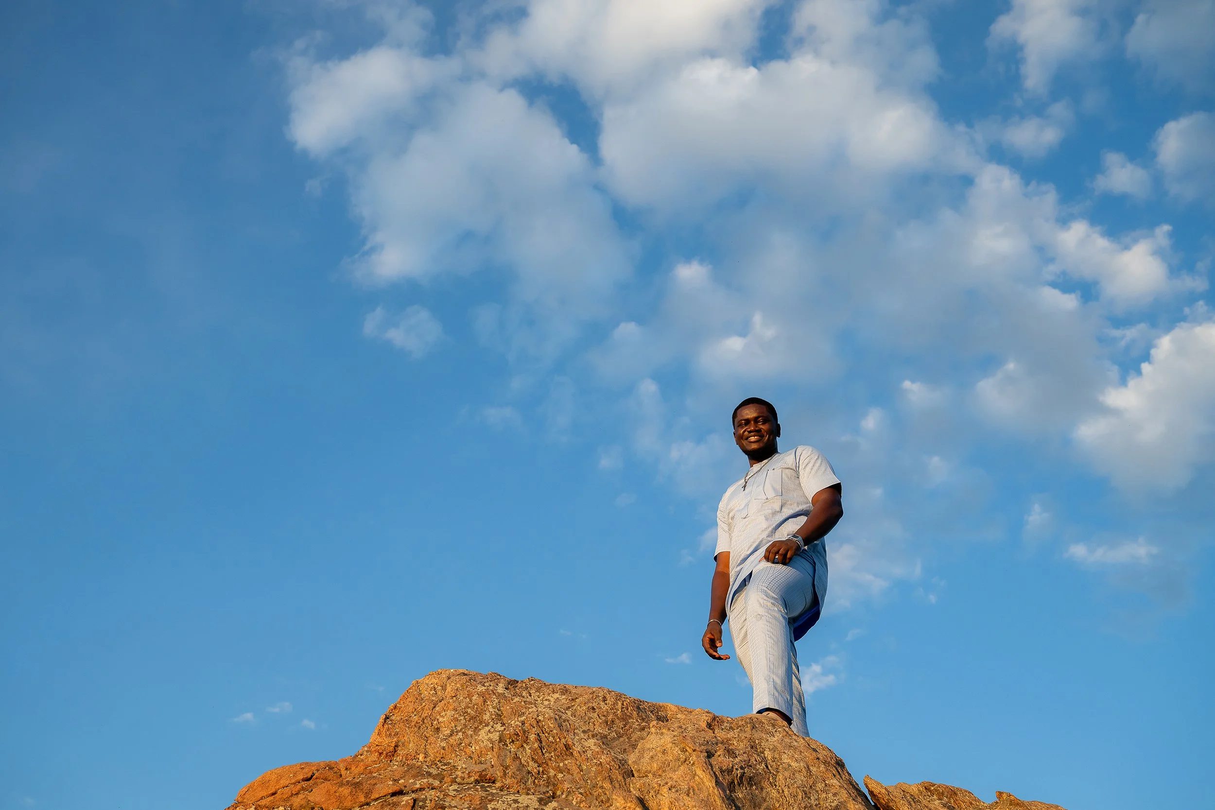 Naturally perfectly posed moment standing on rock outcropping with beautiful big blue Colorado sky at Mount Falcon West Trailhead. Captured by Denver portrait photographer Ryan Kost