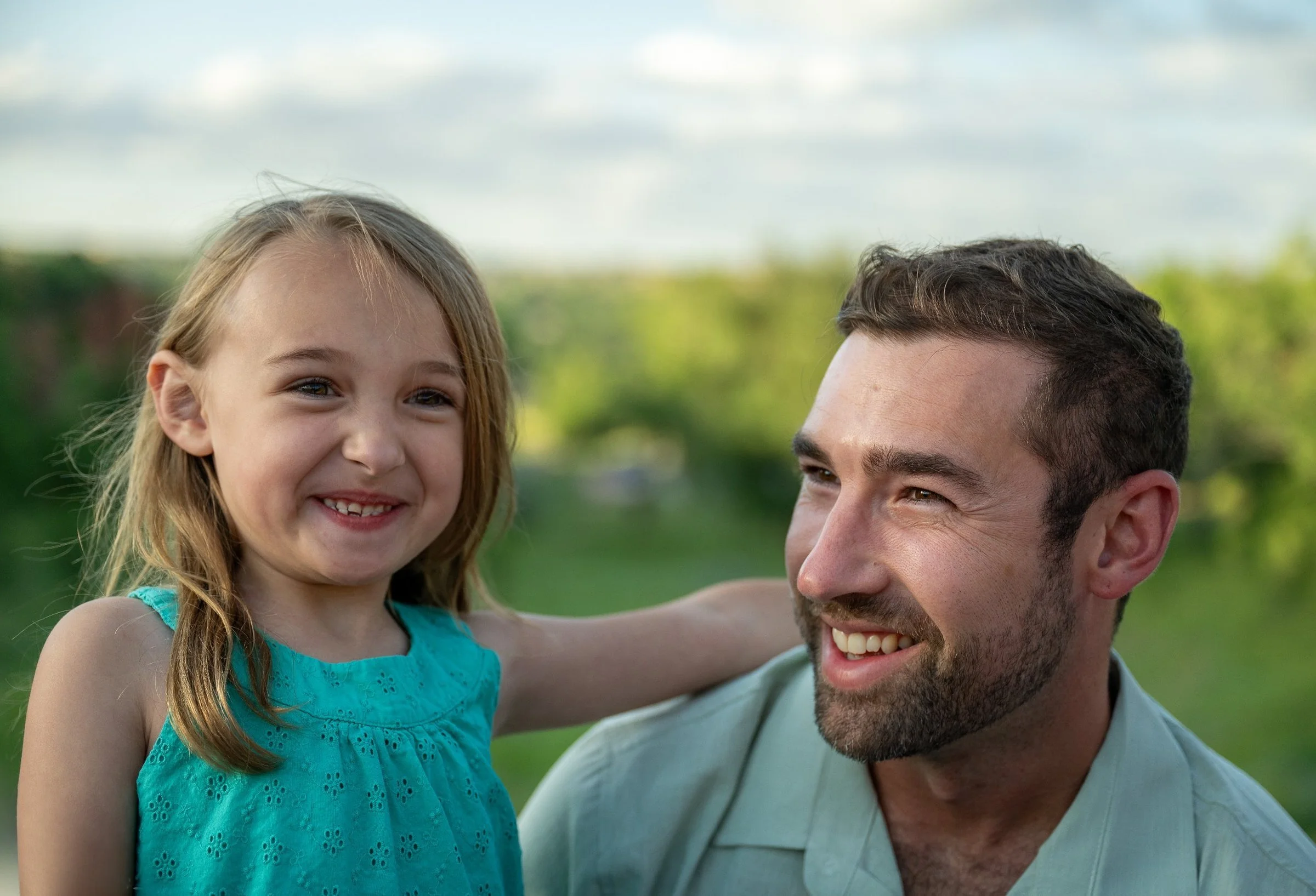 Dad and daughter sharing a candid moment of laughter and love. Family photo session at Red Rock Canyon Open Space in Colorado Springs – captured by Ryan Kost Photography