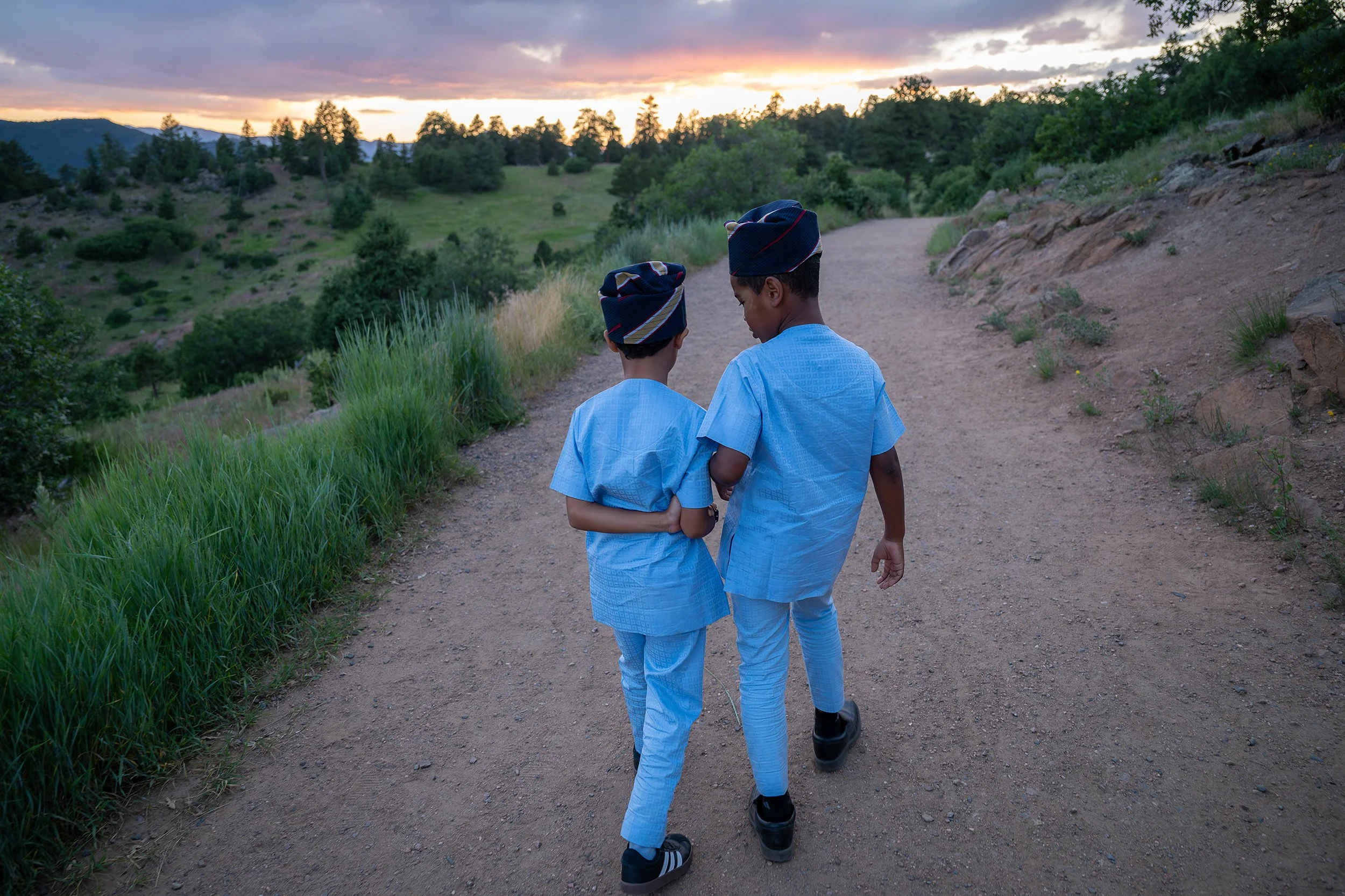 Candid moment of cousins walking a trail together during a summer sunset at Mount Falcon West in Colorado. Captured by Denver family photographer Ryan Kost