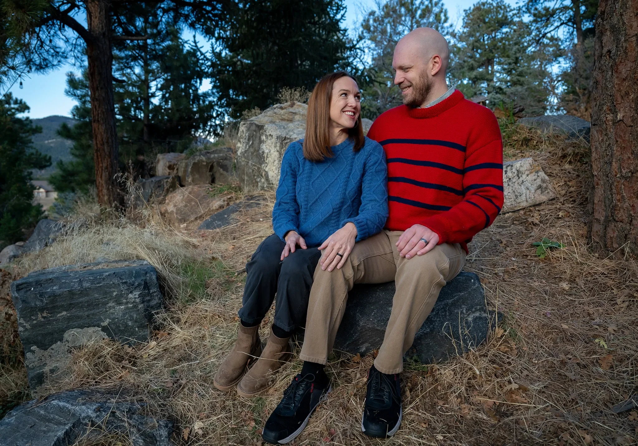 Relaxed couples portrait sitting on rock outside of home in Indian Hills, Colorado.