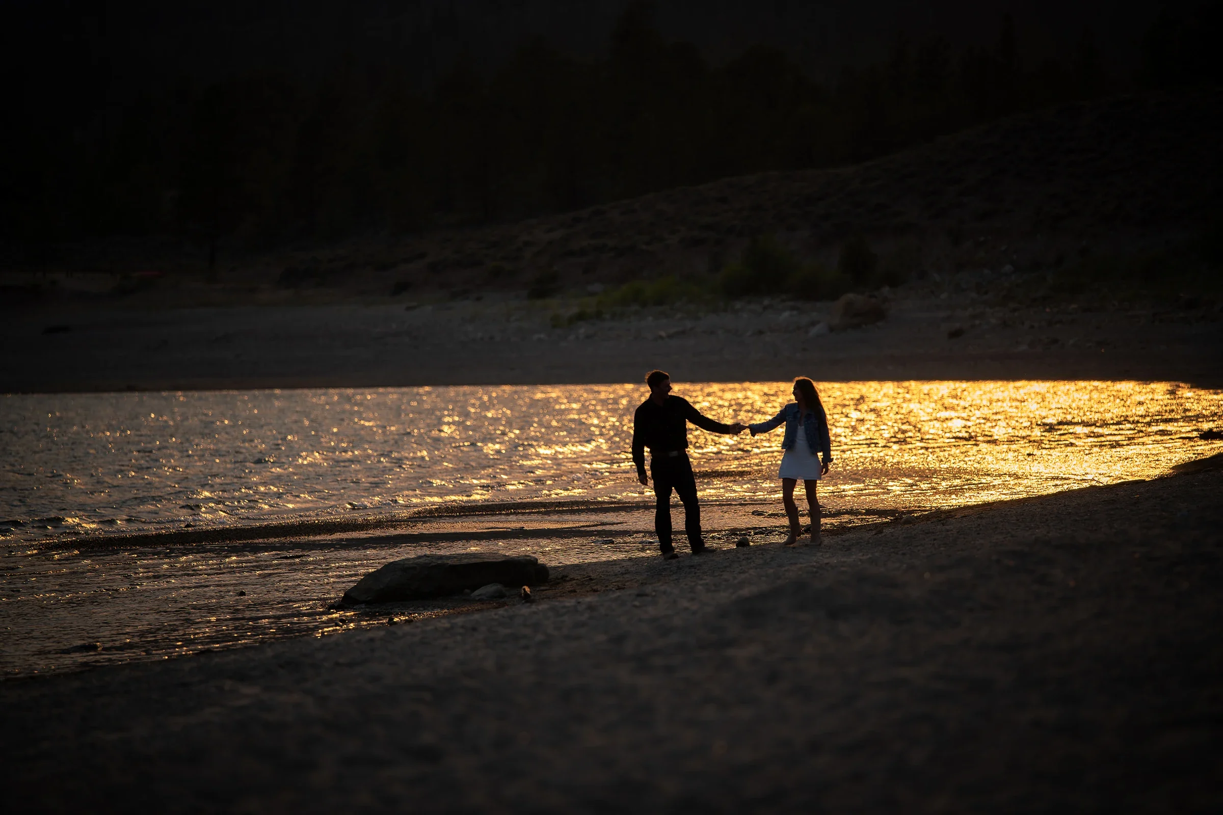 Golden hour silhouette portrait of couple holding hands on the shoreline during a summer elopement at Twin Lakes in the Colorado Rockies.