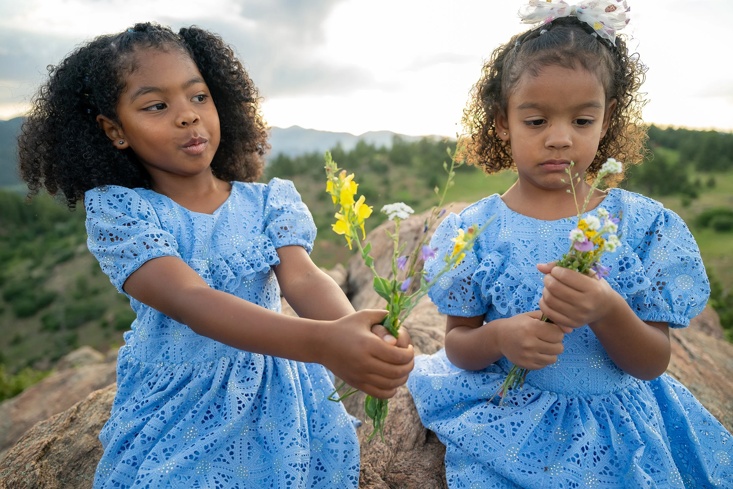 Cousins showing each other wildflowers. Candid natural family photography captured by Ryan Kost at Mount Falcon West Trailhead in Colorado.