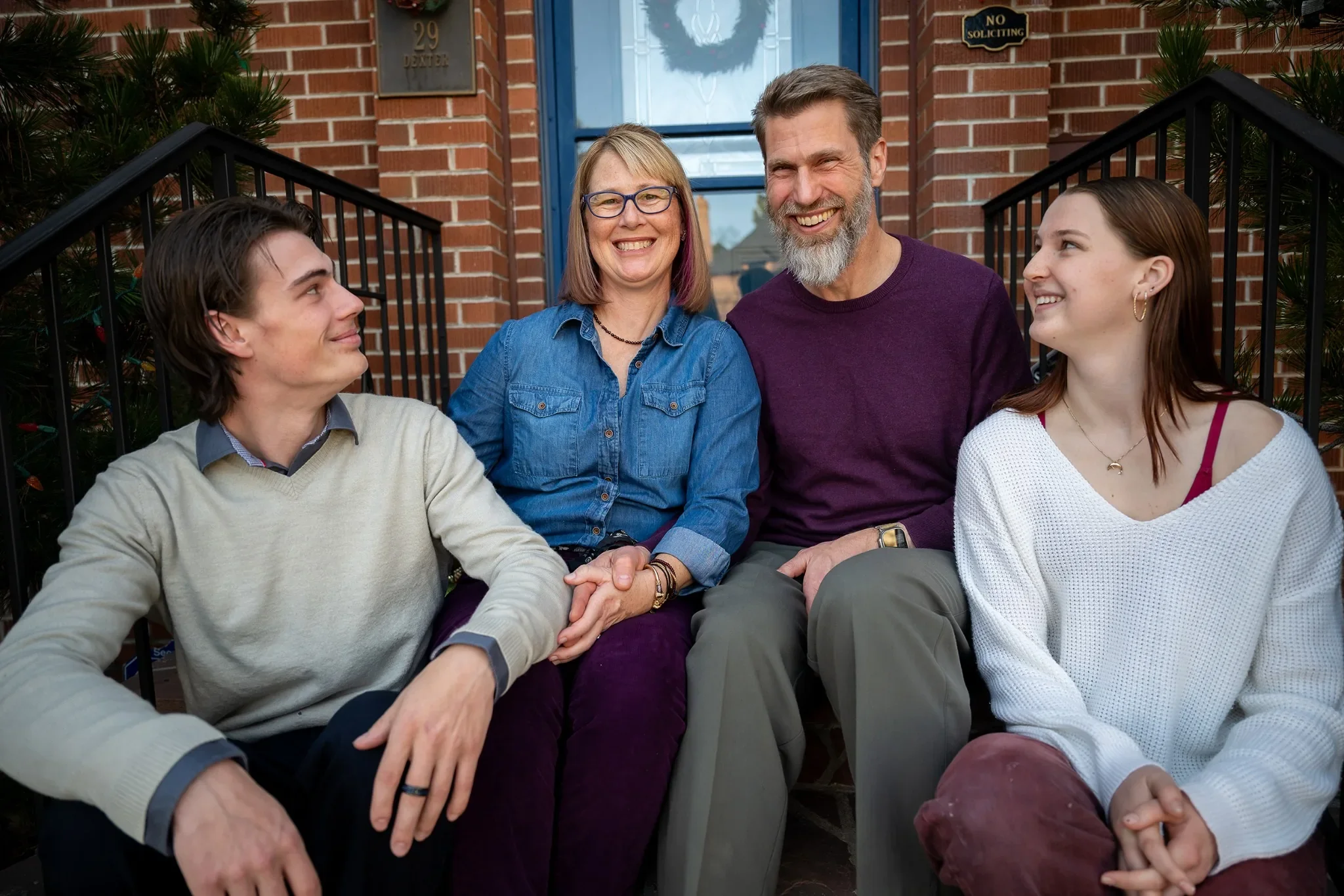 Loving, natural family portrait on front porch of home in Denver, Colorado captured by Ryan Kost.