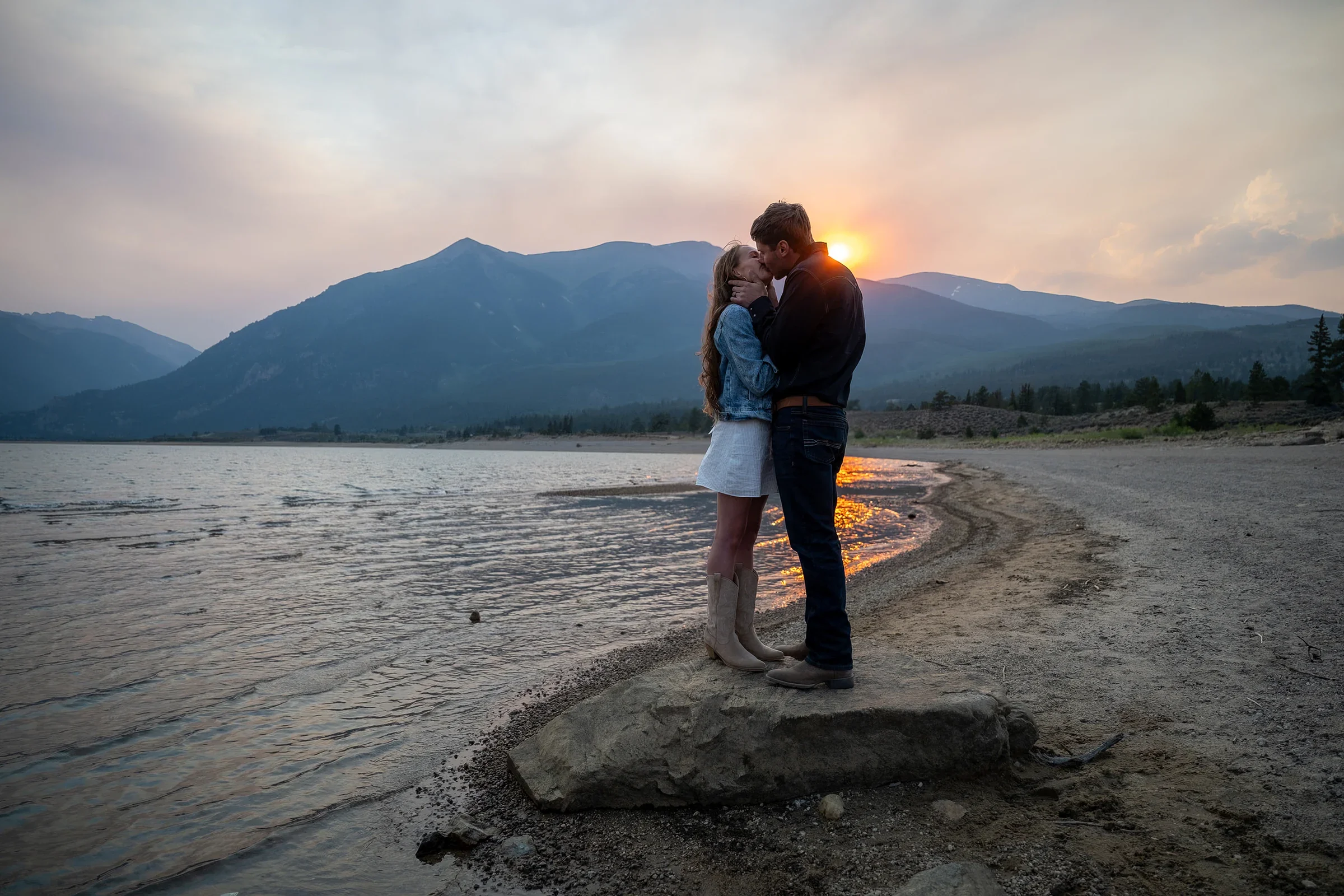 A couple kisses as the sun sets on Twin Lakes in the Colorado Rocky Mountains during a summer elopement captured by Ryan Kost