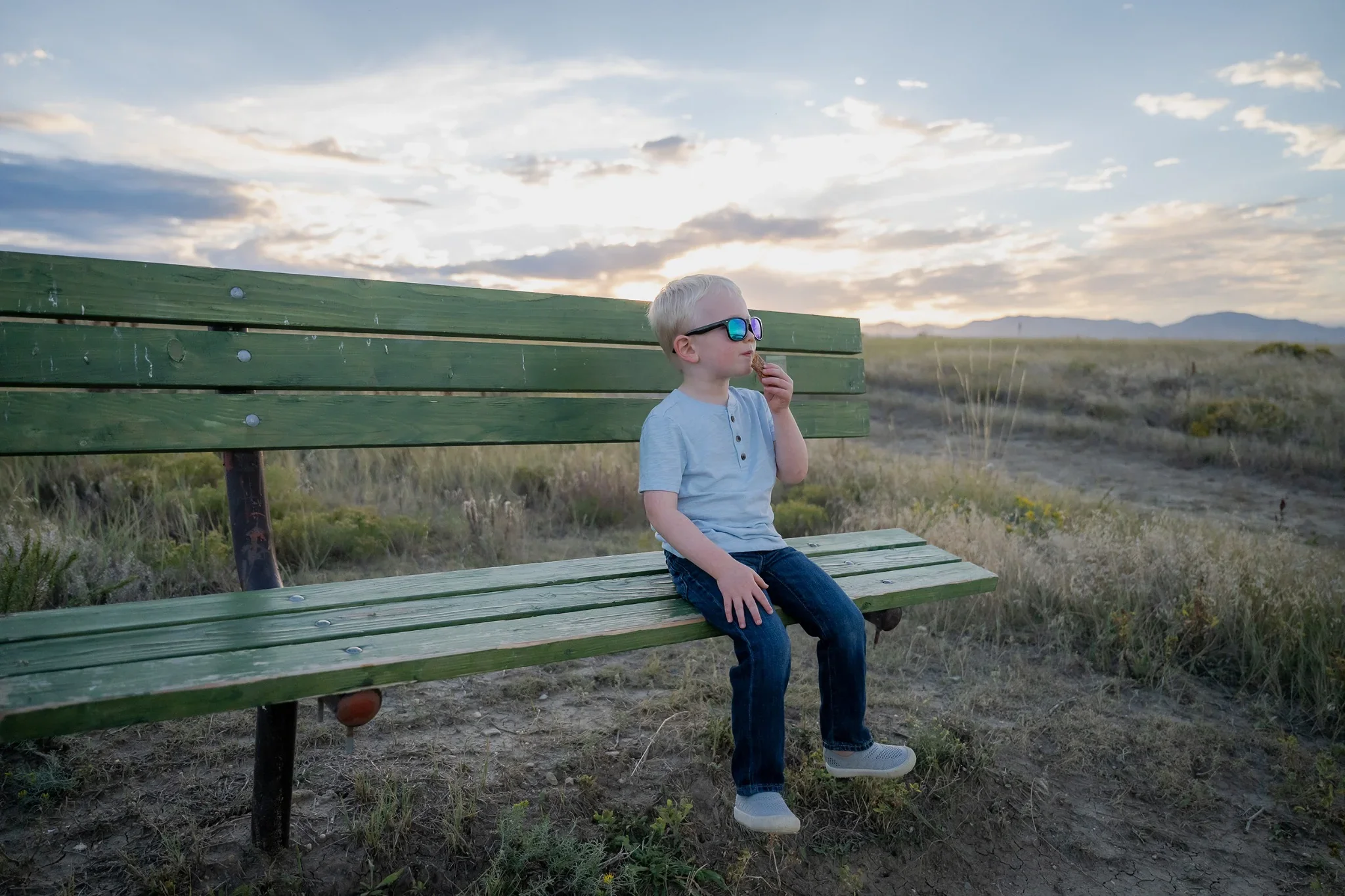 A boy sits with on a park bench eating his candy at Standley Lake in Westminster, Colorado Relaxed, natural family photography captured by Ryan Kost.