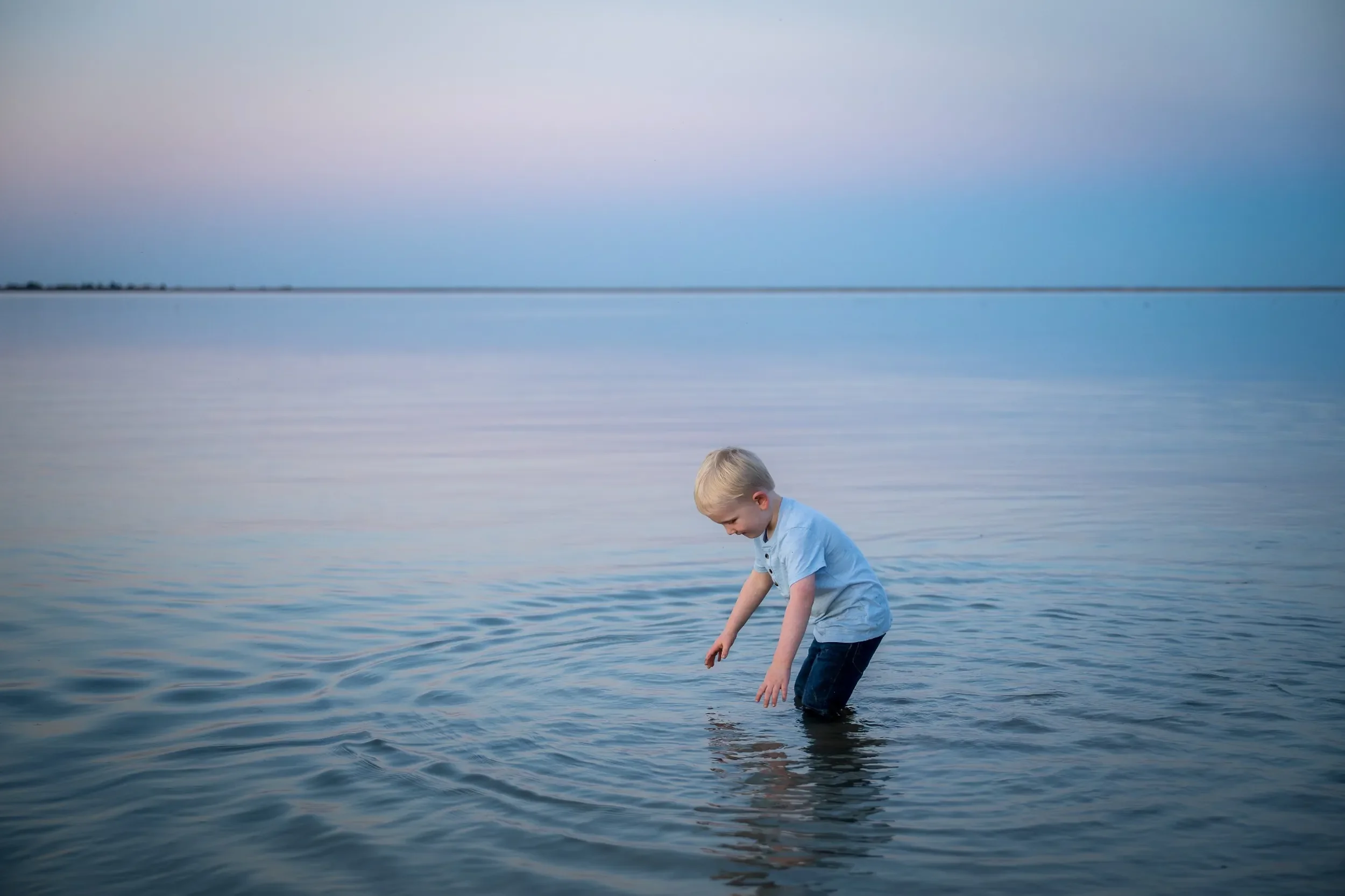 A boy plays in the water during dusk at Standley Lake in Westminster, Colorado Relaxed, natural family photography captured by Ryan Kost.