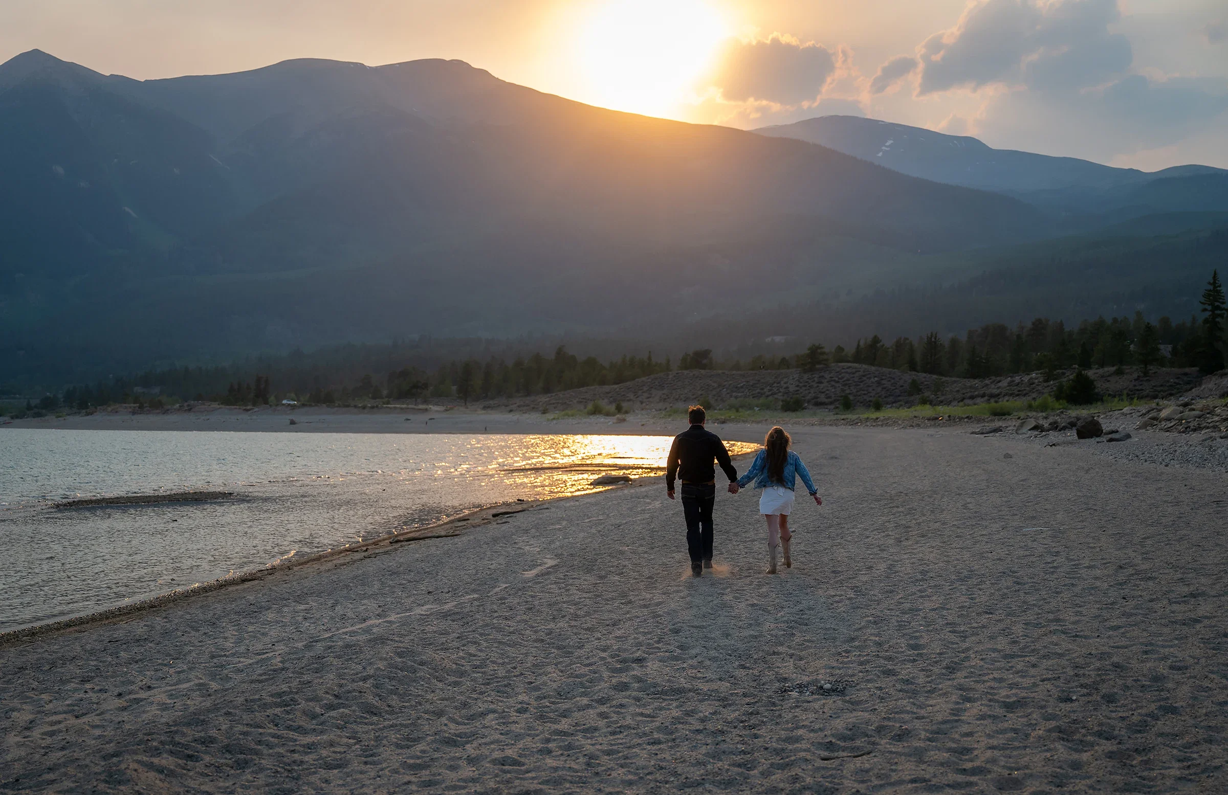 Couple walking the shoreline at sunset during an elopement at Twin Lakes in Colorado.