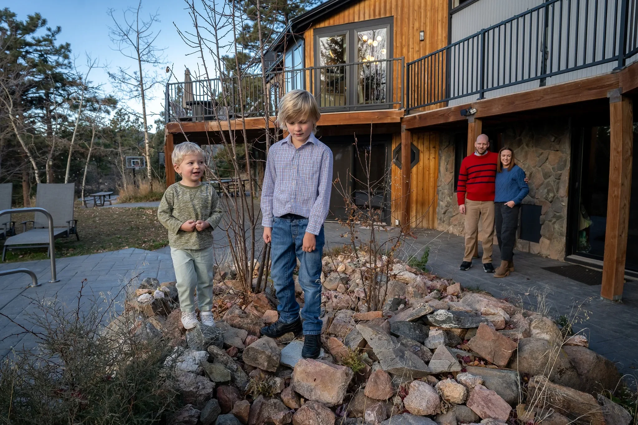 Parents watching their boys play on rocks during a documentary family photo session in Indian Hills, Colorado.