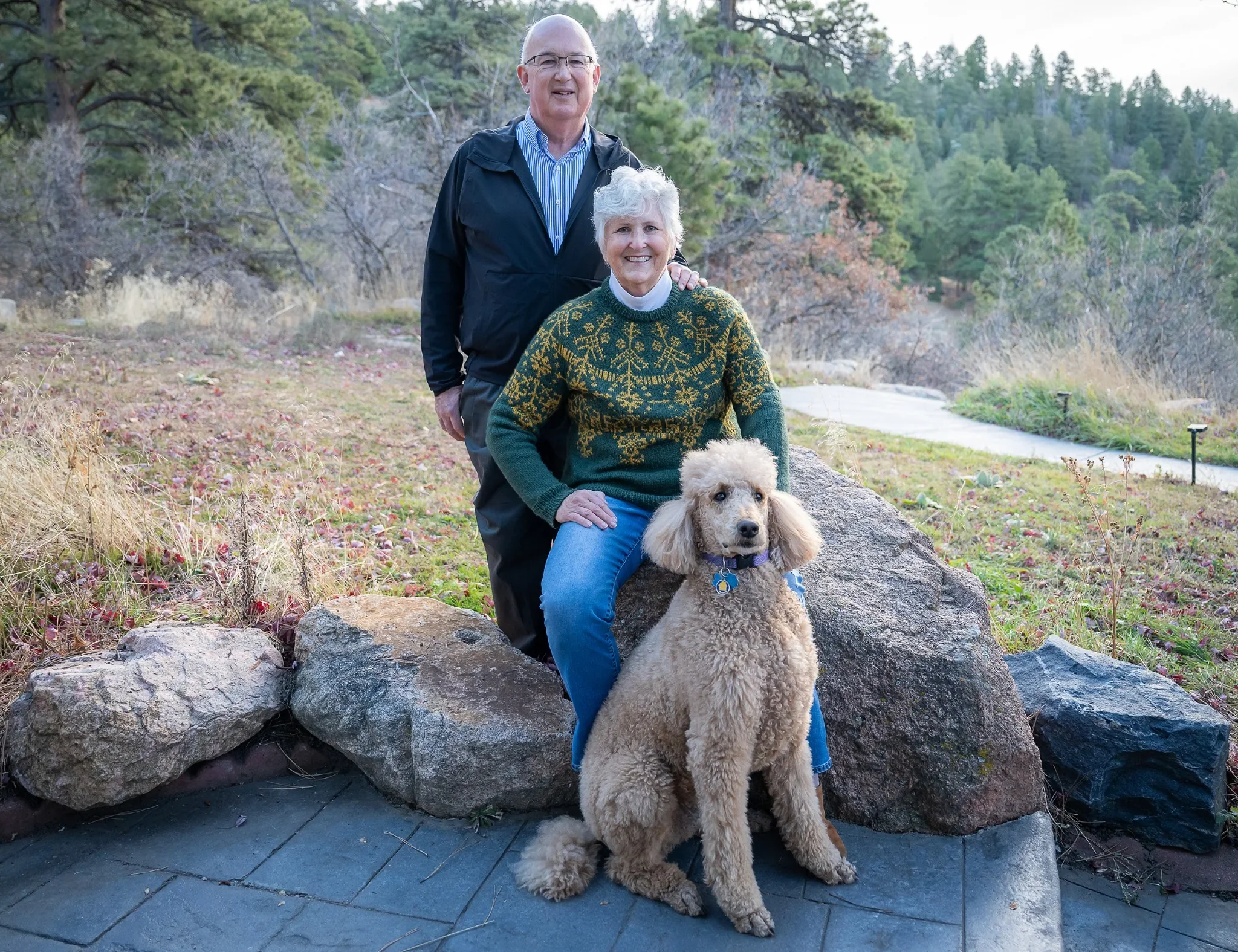 Couples portrait with their poodle outside home in Indian Hills, Colorado.
