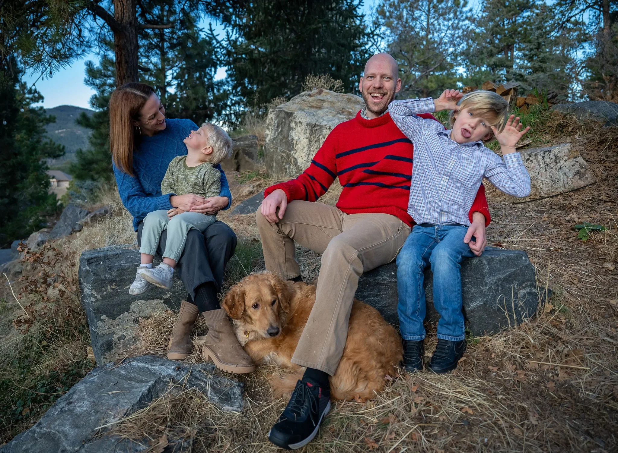 Candid family photo of parents and young children sitting on rocks in the foothills of Indian Hills, Colorado