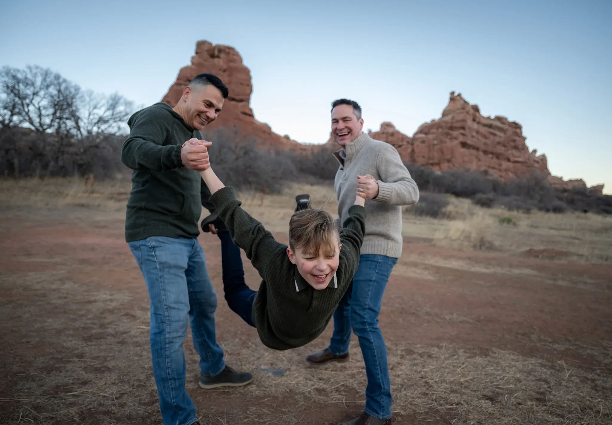 Dad's playfully swinging son during an outdoor family photography session at South Valley Park Littleton Colorado.