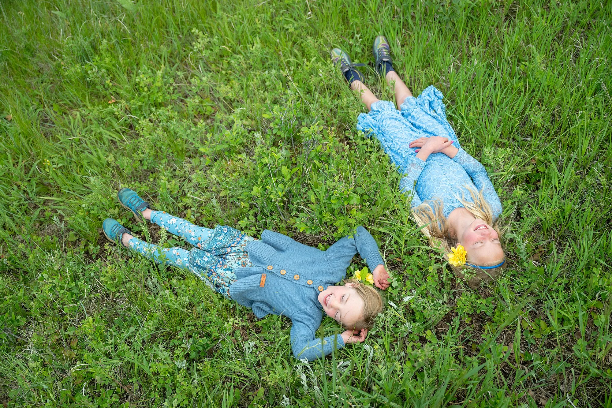 Sisters lay in a summer alpine meadow in their backyard on Lookout Mountain in Golden, Colorado. Relaxed, natural timeless family photography captured by Ryan Kost