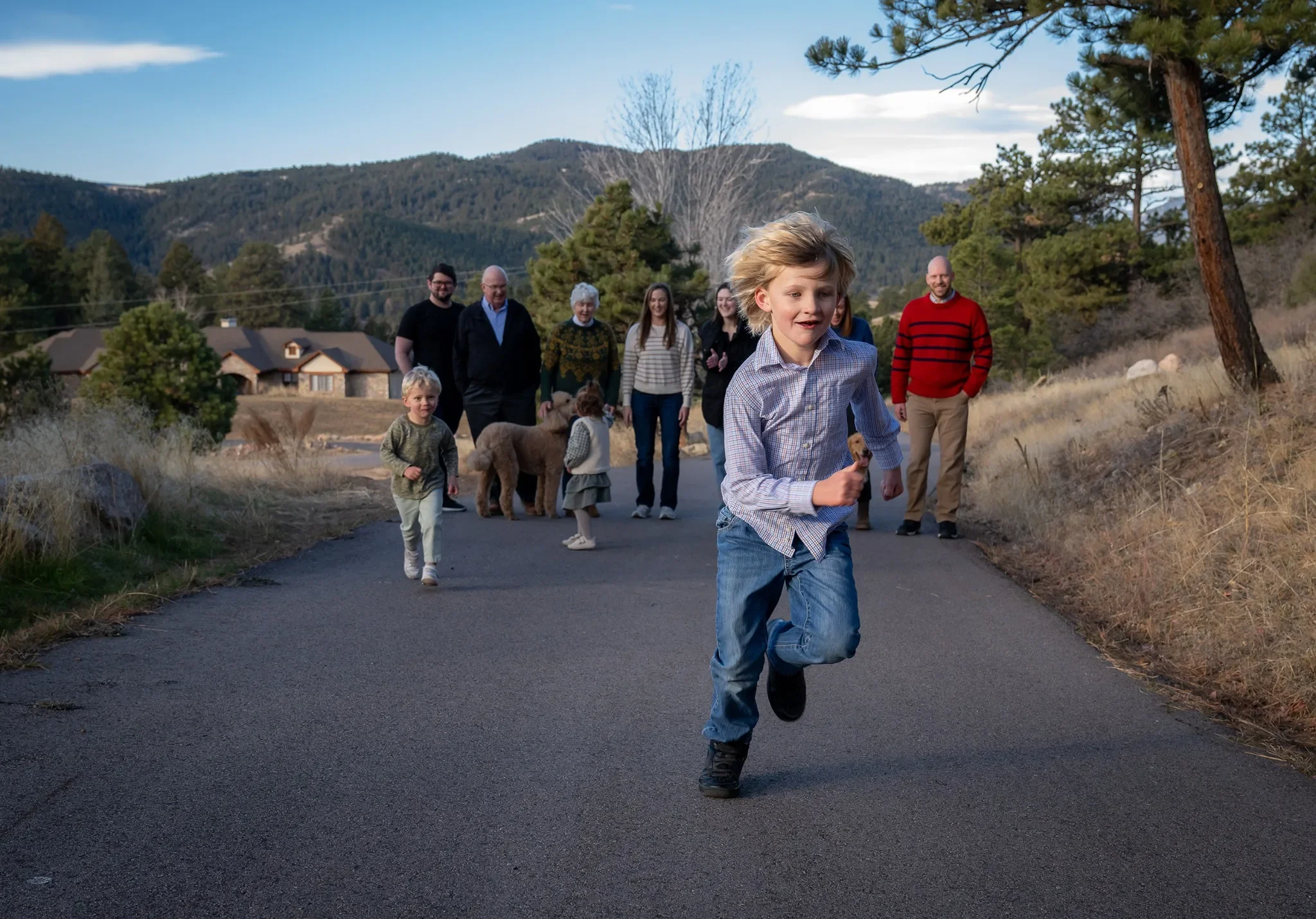 Boy running along a mountain driveway during a family photo session in Indian Hills, Colorado