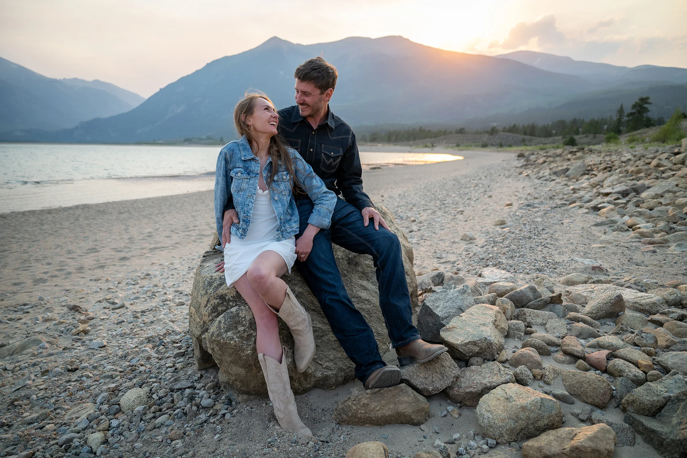 Playful candid portrait of newlyweds sitting together along the shore during their Twin Lakes elopement.