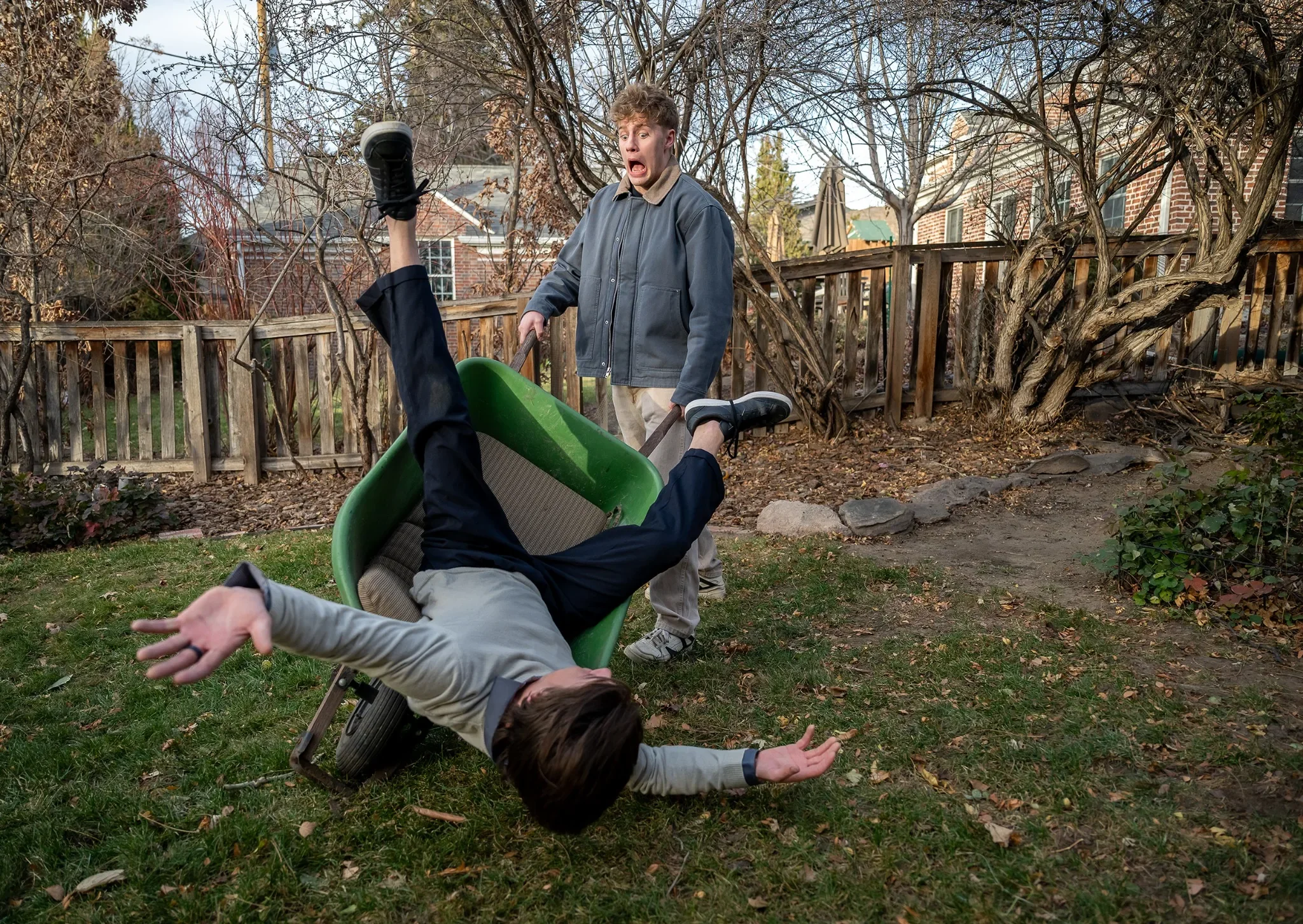 Cousins playing in wheelbarow in backyard during an in home documentary family photo session in Denver, Colorado.