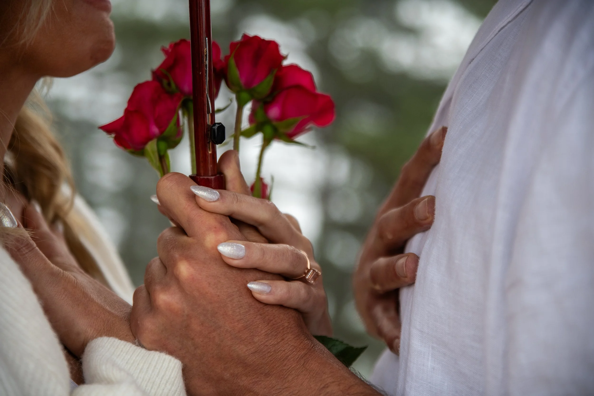 A couple holding hands during a wedding ceremony, with the woman placing a flower bouquet into the man's hand.