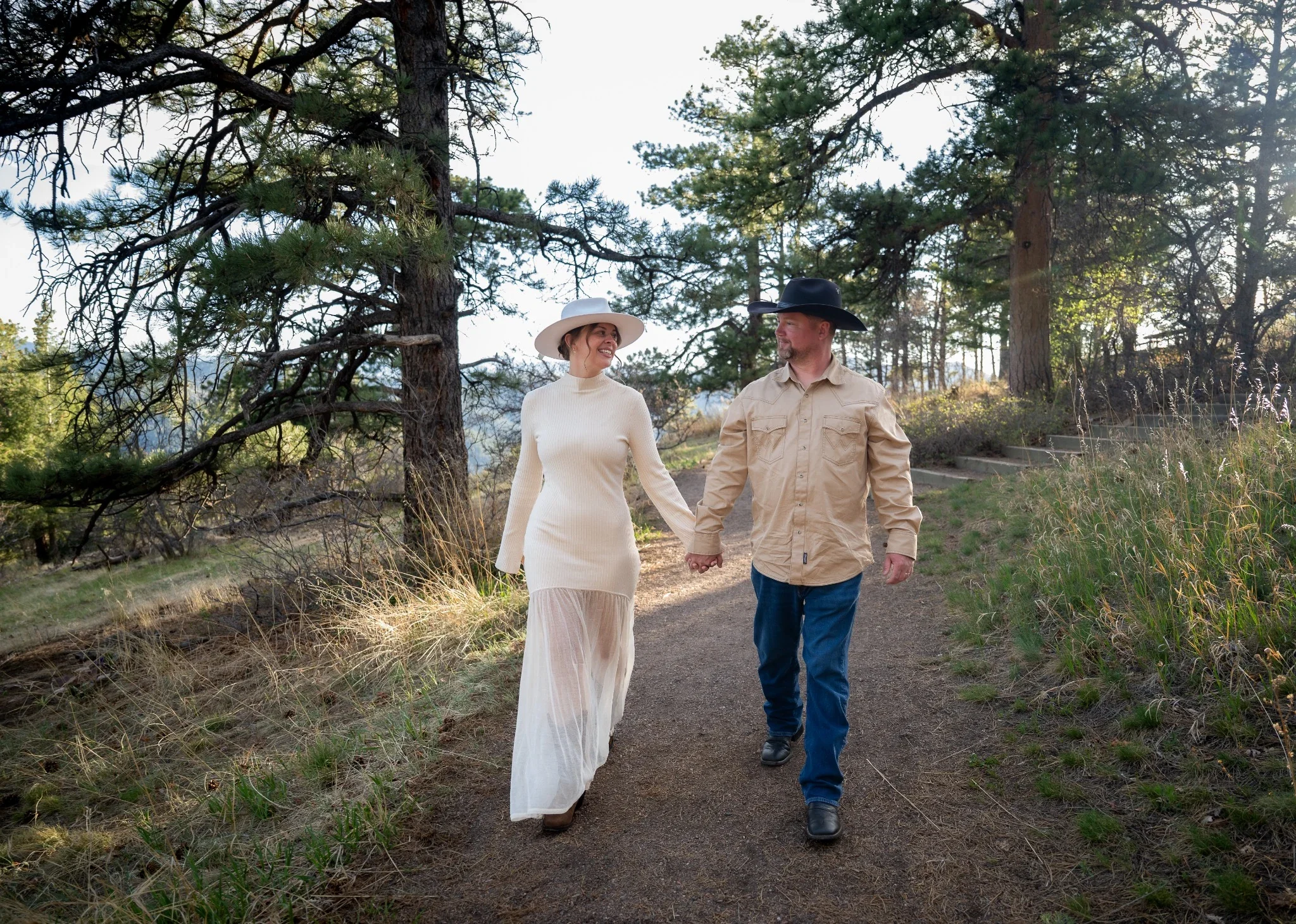 Couple holding hands walking path at Mount Falcon West during a relaxed golden hour family session.
