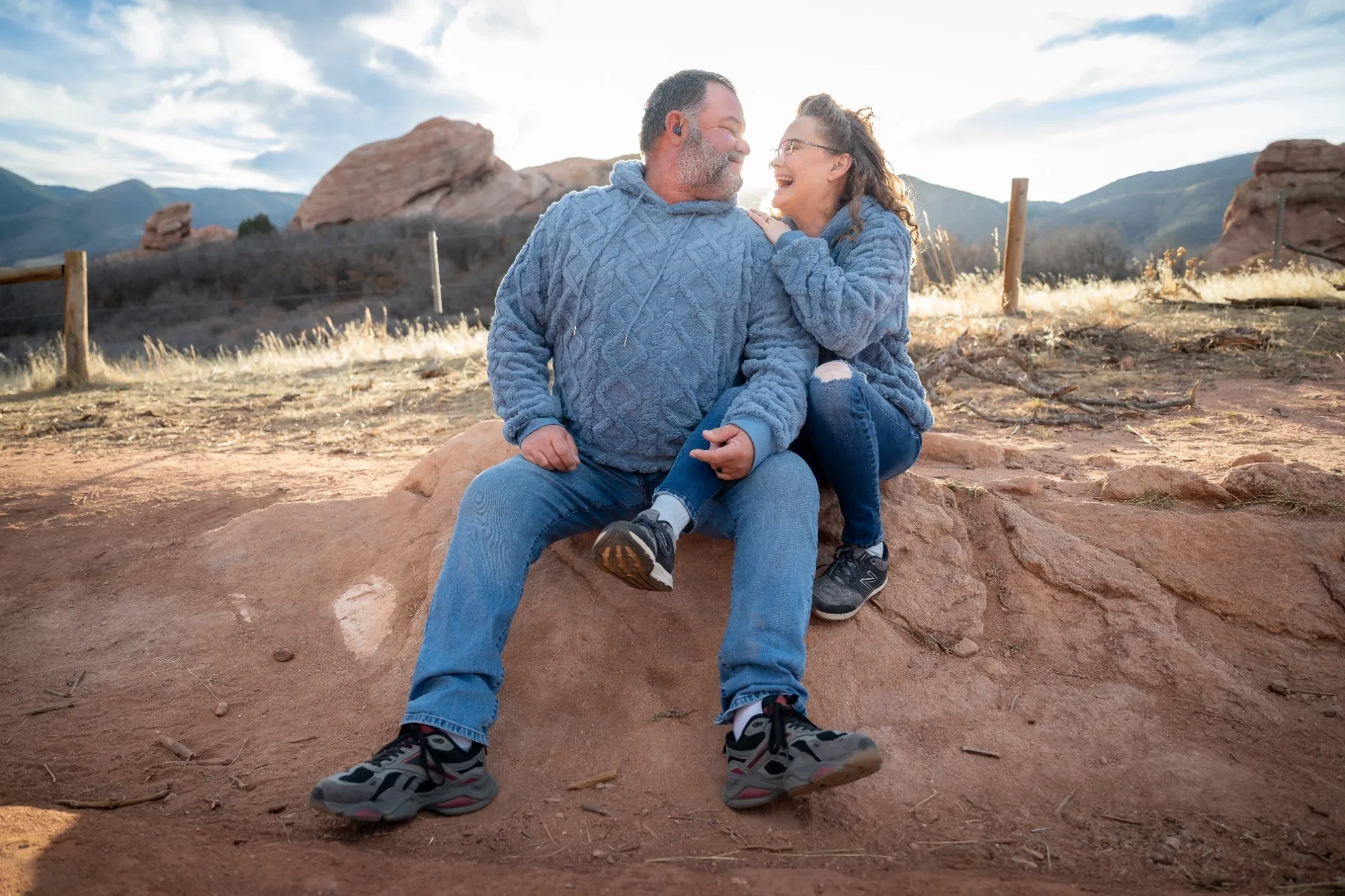 Couples portrait sitting on red rocks during a winter golden hour afternoon family photo session at South Valley Park in Littleton, Colorado captured by Ryan Kost.