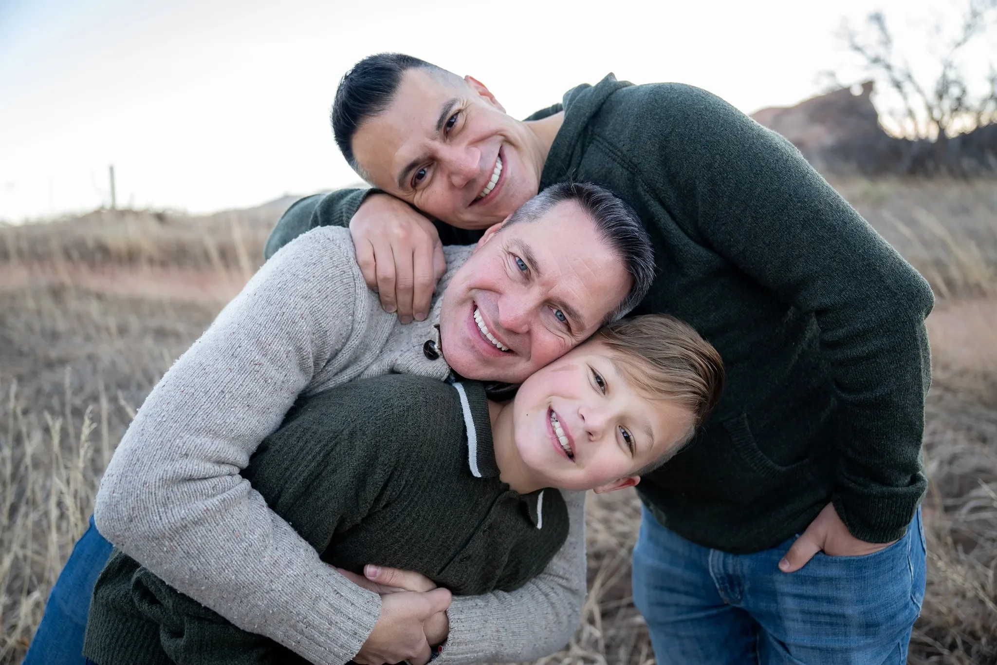 Dad's and son hugging tightly during a relaxed outdoor winter family photo session at South Valley Park in Littleton, Colorado