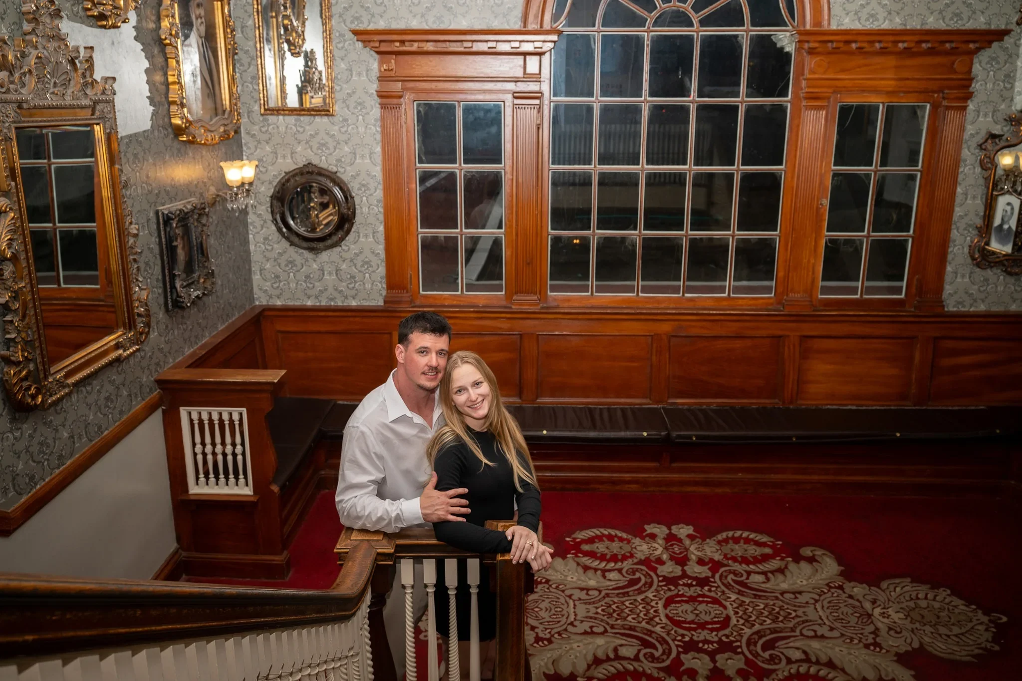 Couple's engagement portrait on staircase landing inside the history Stanley Hotel in Estes Park, Colorado captured by Ryan Kost.